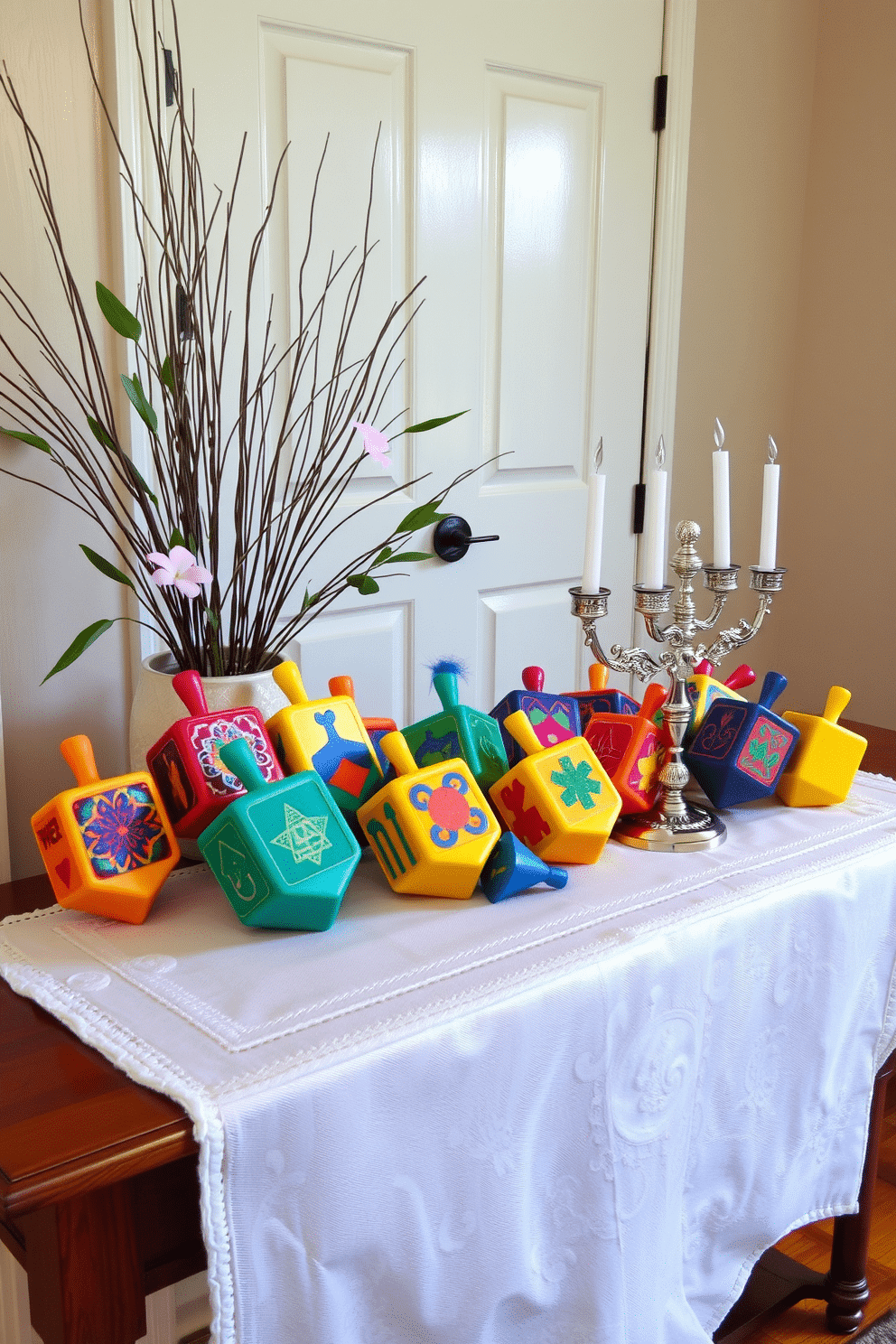 A beautifully decorated entryway table features an array of colorful decorative dreidels, each showcasing intricate designs and vibrant hues. The table is adorned with a soft, white table runner, and a small, elegant menorah sits beside the dreidels, creating a warm and inviting atmosphere for Hanukkah celebrations.