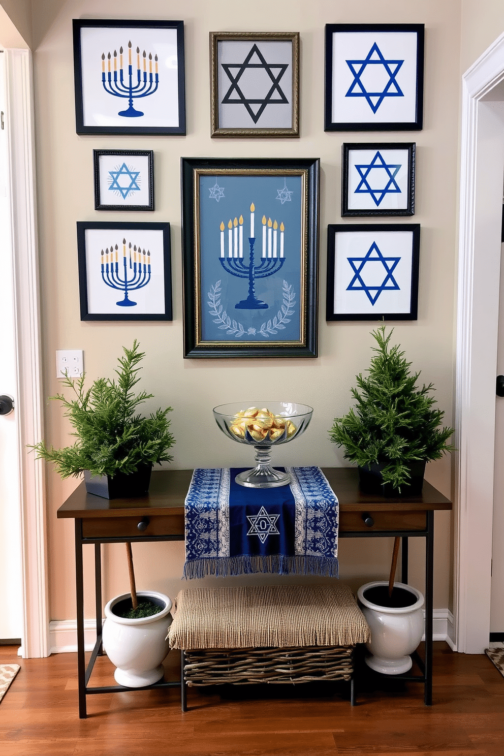 A cozy entryway adorned with seasonal artwork featuring Hanukkah symbols. The walls are decorated with framed pieces showcasing menorahs, dreidels, and Star of David motifs, creating a festive atmosphere. A welcoming console table is placed against the wall, topped with a decorative runner in blue and silver. Flanking the table are potted evergreen arrangements, and a beautiful glass bowl filled with gelt adds a touch of charm.