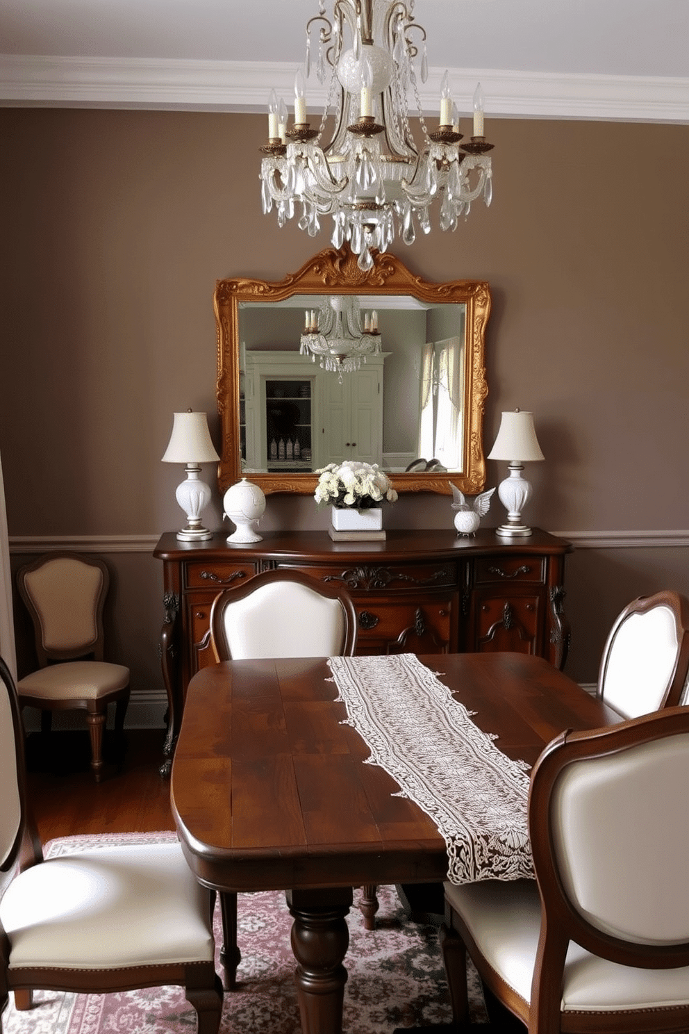 A vintage sideboard with intricate carvings and a rich mahogany finish serves as the focal point of the dining room. Surrounding it are elegant upholstered chairs in a soft cream fabric, complemented by a rustic wooden dining table adorned with a delicate lace table runner. The walls are painted in a warm taupe, creating a cozy ambiance, while a stunning chandelier with crystal accents hangs above the table. A large framed mirror with an ornate gold frame reflects the beauty of the room, enhancing the vintage charm and inviting warmth.