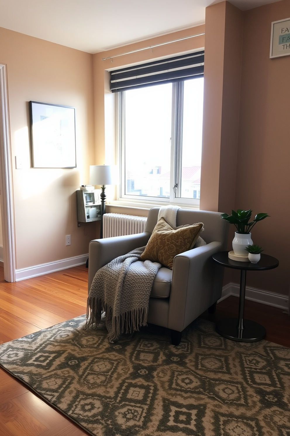 A cozy living room setting in a stylish apartment. There's a plush armchair in a soft fabric, draped with a knitted blanket, positioned next to a small side table. The walls are painted in a warm beige tone, complemented by a large window letting in natural light. A patterned area rug covers the hardwood floor, and decorative cushions add a pop of color to the chair.