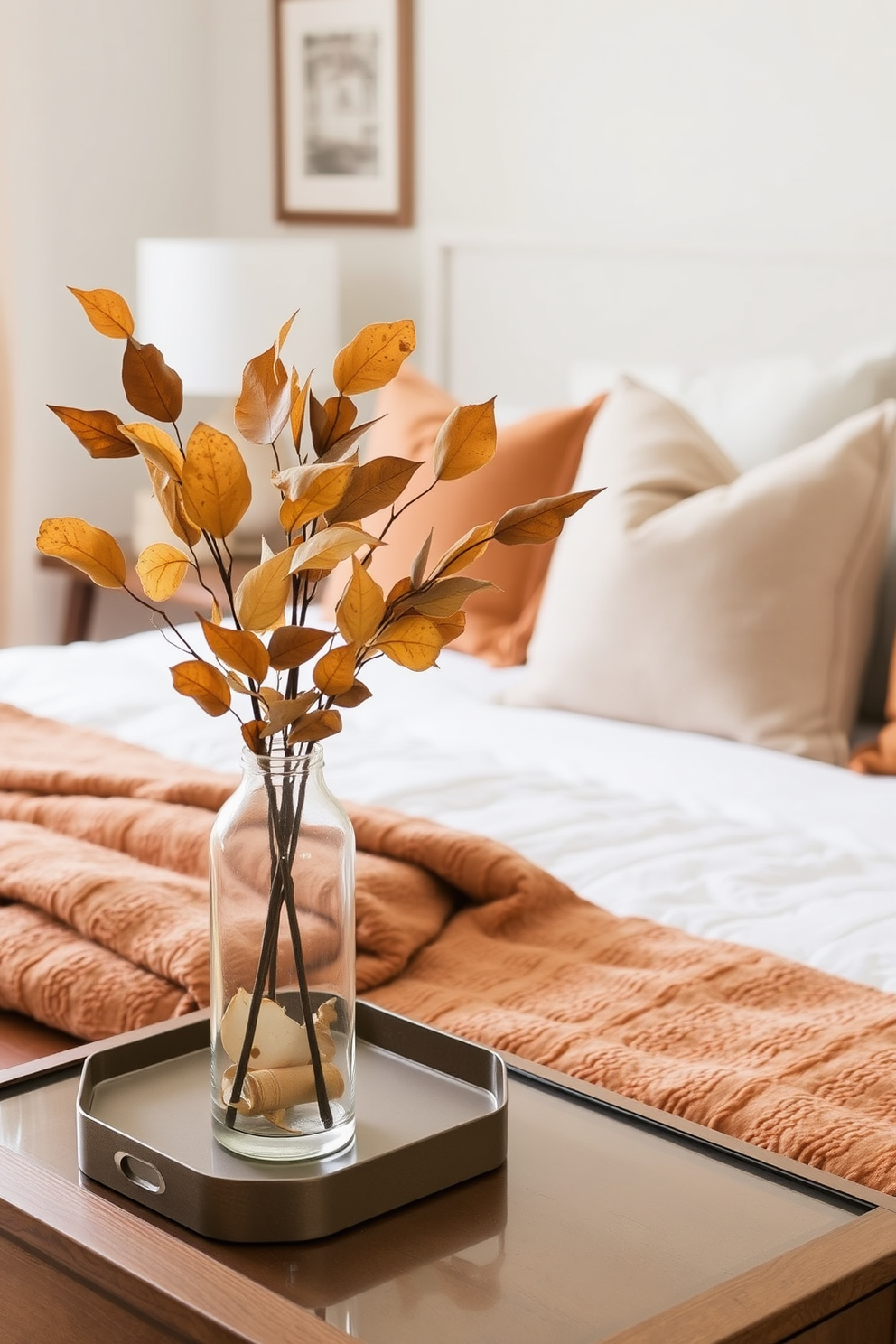 A cozy fall bedroom setting featuring dried leaves elegantly arranged in glass vases placed on nightstands. The bed is adorned with warm-toned blankets and plush pillows, creating an inviting atmosphere perfect for the season.