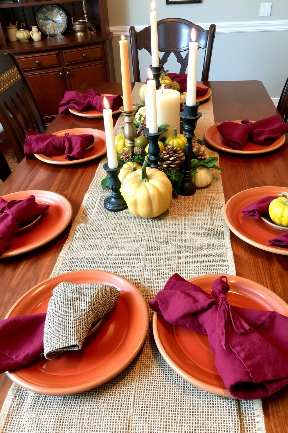 A beautiful dining table set with earthy tones creates a warm and inviting atmosphere. The table is adorned with a rustic burlap table runner and handmade ceramic plates in shades of terracotta and olive green. Centerpieces feature a mix of seasonal gourds and candles in varying heights, enhancing the fall theme. Soft, textured napkins in deep burgundy are elegantly folded beside each plate, adding a touch of sophistication.