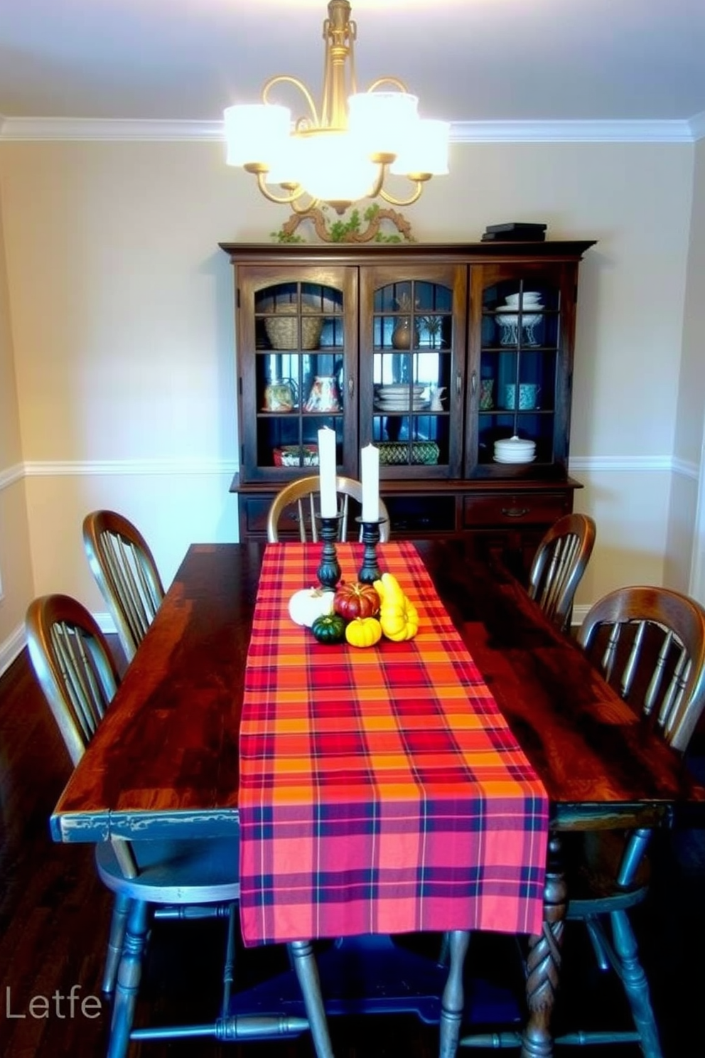 A warm and inviting dining room features a rustic wooden table adorned with a vibrant plaid table runner in shades of red and orange. Surrounding the table are mismatched vintage chairs, each with its own unique charm, creating a cozy atmosphere perfect for family gatherings. The walls are painted in a soft cream color, complementing the rich hues of the table runner. Centered on the table is a centerpiece of seasonal gourds and candles, enhancing the fall theme and inviting warmth into the space.