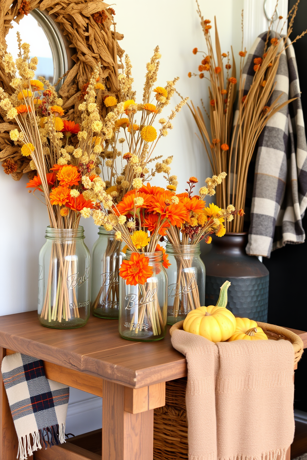 A cozy fall entryway adorned with mason jars filled with dried flowers in various shades of orange and yellow. The jars are arranged on a rustic wooden bench, complemented by a woven basket filled with seasonal gourds and a soft plaid throw draped over the side.