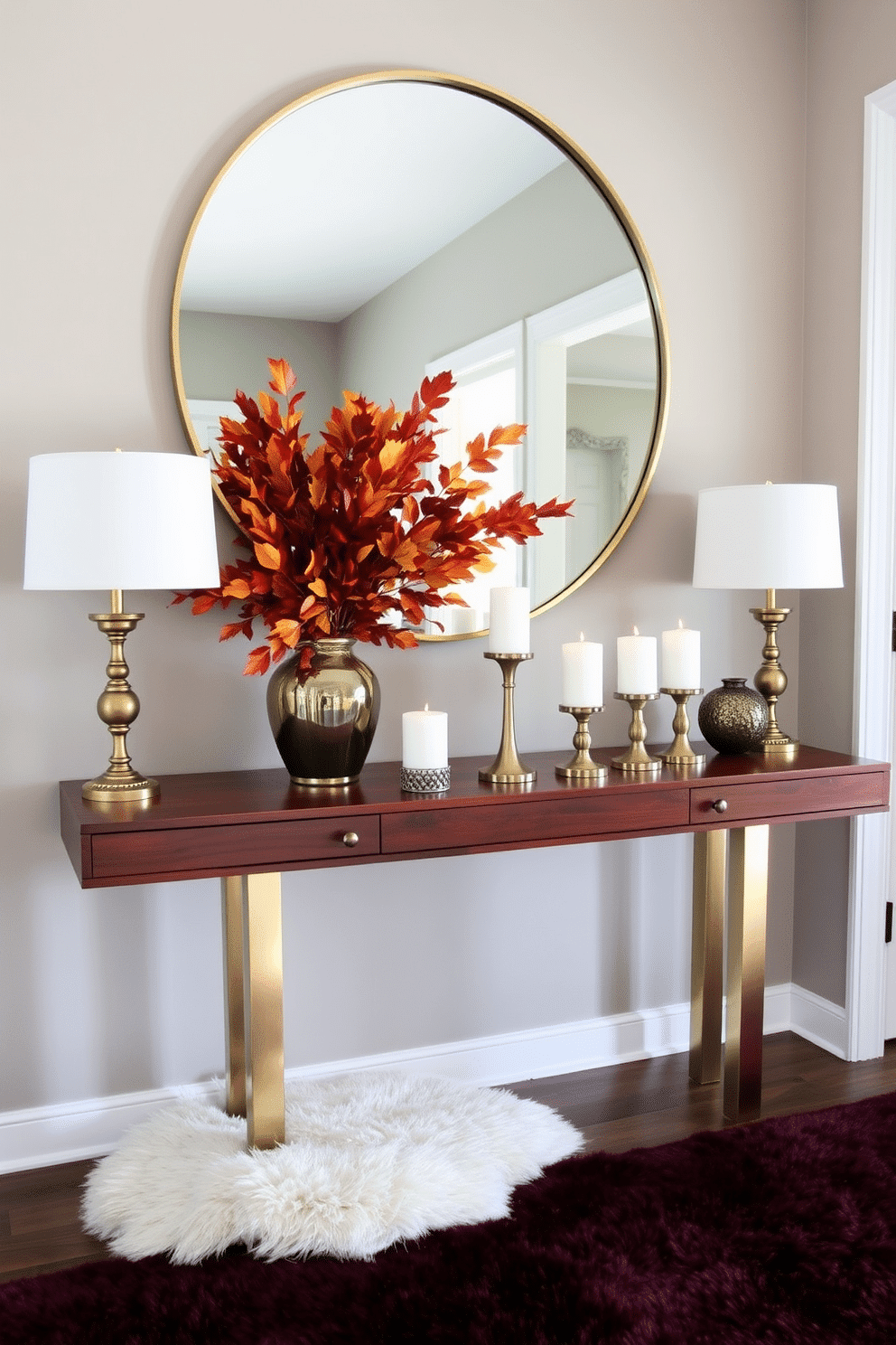 A stylish fall entryway featuring a rich wooden console table adorned with metallic accents. A large round mirror with a sleek gold frame hangs above the table, reflecting the warm tones of autumn leaves arranged in a decorative vase. The floor is covered with a plush area rug in deep burgundy, providing a cozy welcome. On the table, a collection of elegant candles in varying heights adds a sophisticated glow to the space.