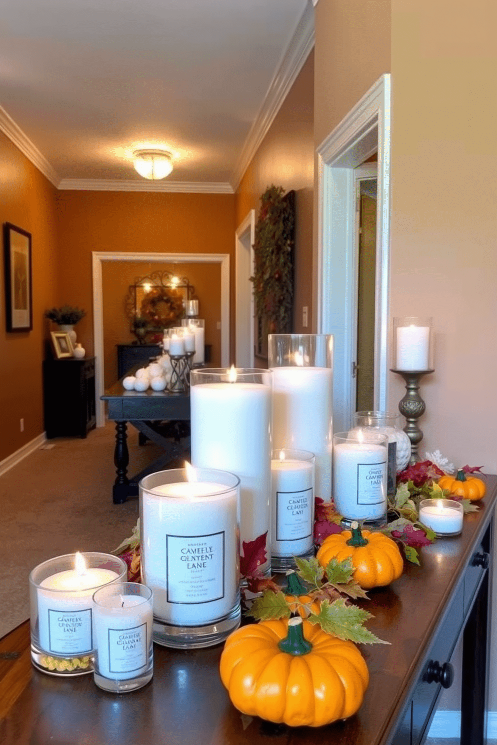 Seasonal scented candles in various sizes are placed on surfaces throughout the hallway. The candles are arranged on a wooden console table adorned with autumn leaves and small pumpkins for a festive touch. The walls of the hallway are painted in warm earthy tones, creating a cozy atmosphere. Soft, ambient lighting highlights the candles, casting a gentle glow that enhances the seasonal decor.