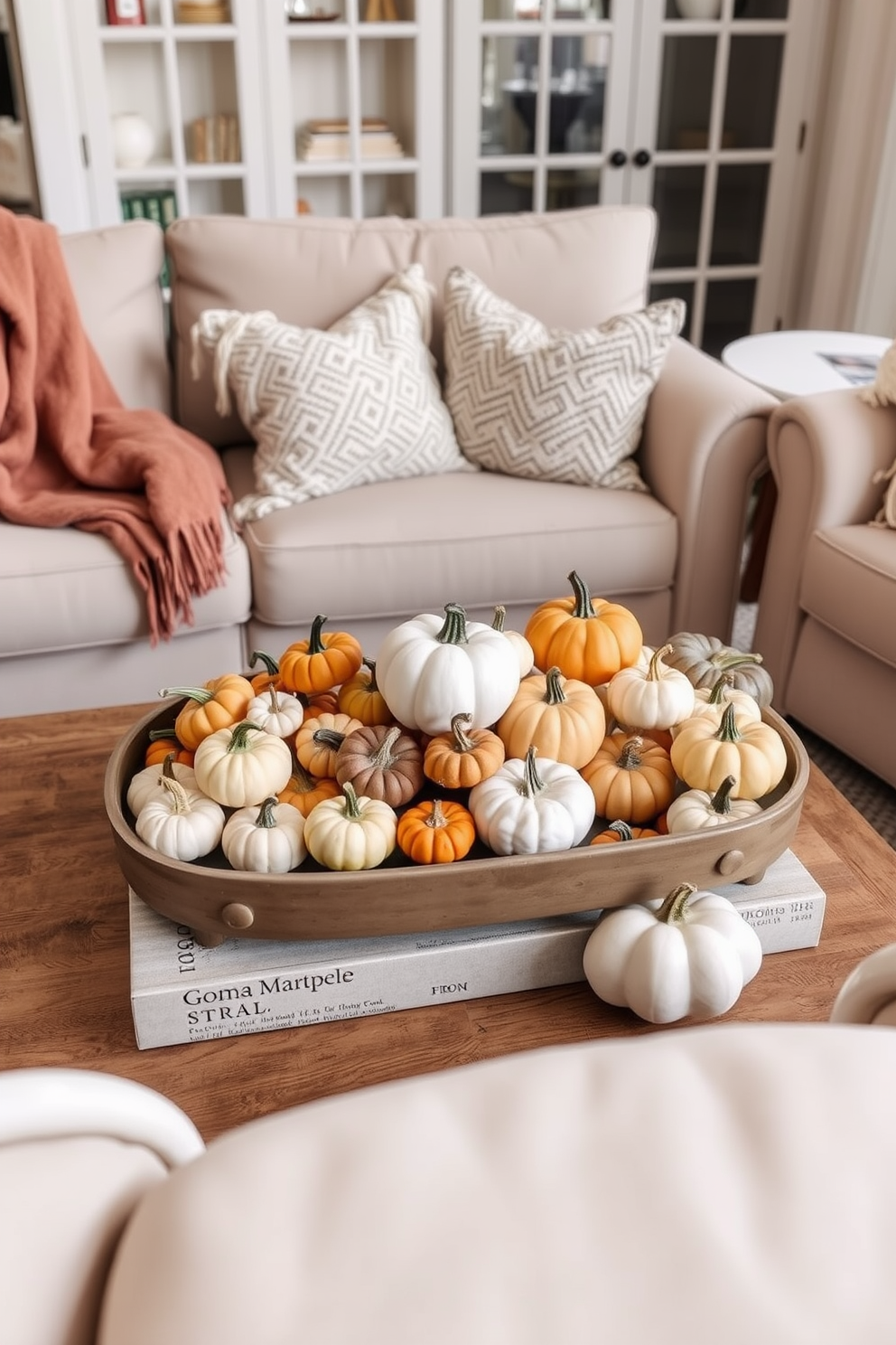 A cozy living room setting featuring a coffee table adorned with an assortment of mini pumpkins in various sizes and colors. Surrounding the table are plush, neutral-toned sofas with soft throw blankets draped over the arms, creating an inviting atmosphere for fall gatherings.