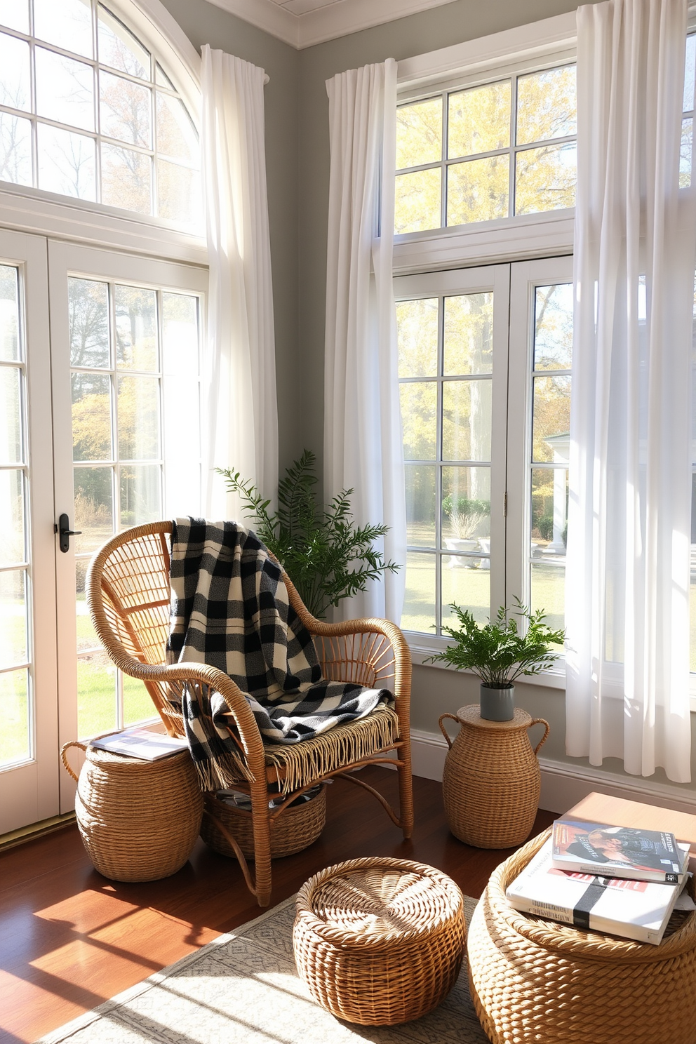 A cozy sunroom filled with natural light. There are large windows dressed with sheer white curtains, allowing the warm fall sunlight to filter in. In one corner, a comfortable rattan chair is paired with a soft, plaid throw blanket. Woven baskets are placed under the coffee table for stylish storage of magazines and blankets.