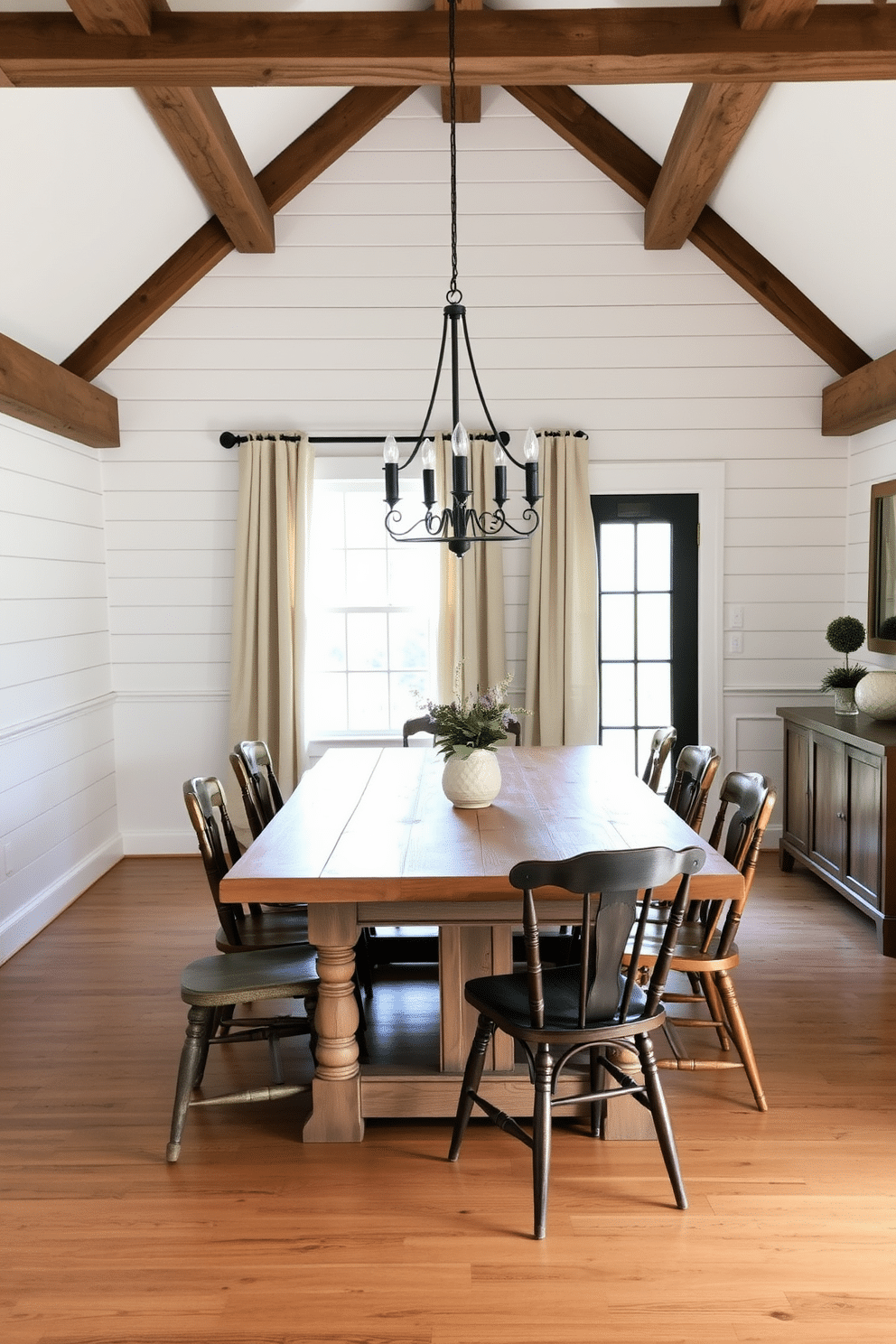 Decorative wall paneling adds a touch of elegance and depth to a farmhouse dining room. The walls are adorned with white shiplap paneling, complemented by rustic wood beams that enhance the cozy atmosphere. A large farmhouse table made of reclaimed wood sits at the center, surrounded by mismatched chairs for a charming, eclectic look. Soft, natural lighting filters through sheer linen curtains, creating a warm and inviting dining space perfect for gatherings.