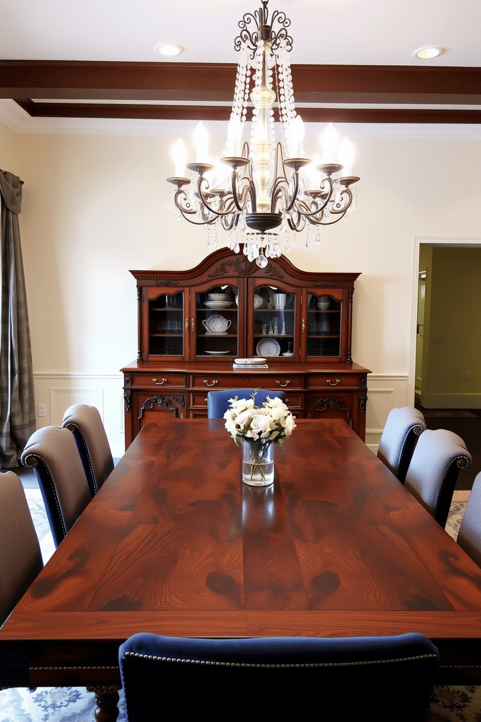 A stunning formal dining room features an antique sideboard crafted from rich mahogany, adorned with intricate carvings and brass hardware. The sideboard is positioned against a soft cream wall, enhancing its elegance while providing ample storage for fine china and linens. A large, polished dining table made of reclaimed wood takes center stage, surrounded by upholstered chairs in a deep navy fabric. Above the table, a grand chandelier with crystal accents casts a warm glow, creating an inviting atmosphere for dinner parties and family gatherings.