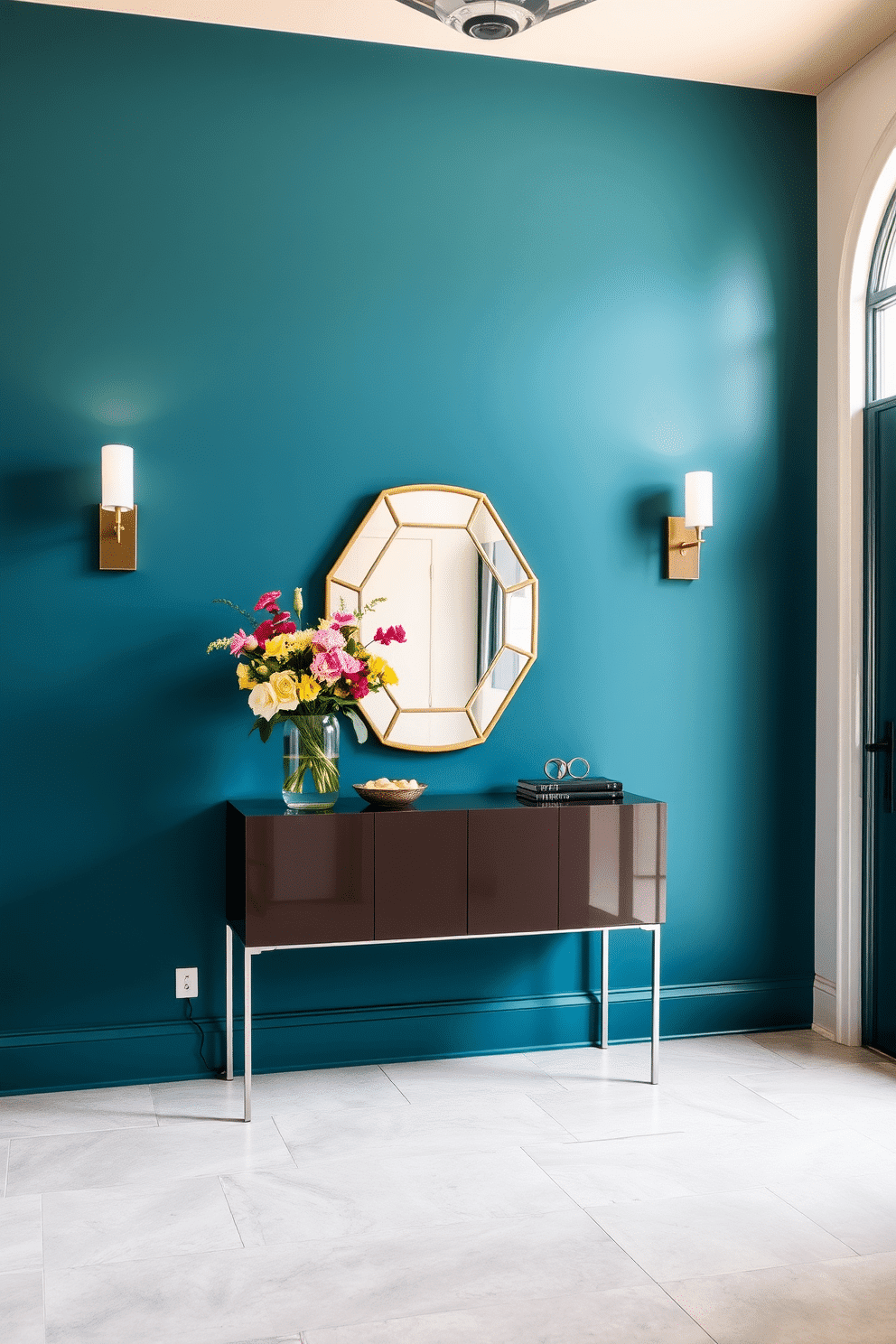 A striking foyer features a bold color accent wall painted in deep teal, creating a dramatic first impression. A sleek console table with a glossy finish sits against the wall, adorned with a statement mirror and a vibrant arrangement of fresh flowers. The floor is laid with large-format tiles in a light gray tone, providing a contemporary contrast to the rich wall color. Flanking the entrance, stylish sconces cast a warm glow, enhancing the inviting atmosphere of this sophisticated space.