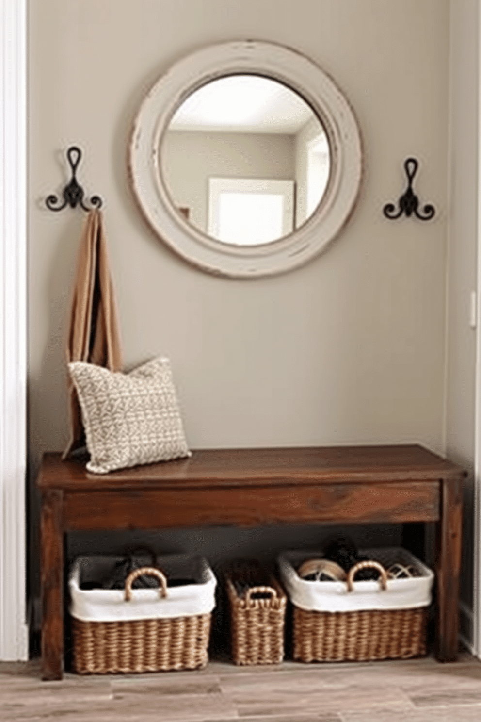 A rustic wooden bench with storage is positioned against the wall in the foyer, providing both functionality and charm. Above the bench, a large round mirror with a distressed frame reflects natural light, enhancing the welcoming atmosphere of the entryway. Flanking the bench are decorative hooks for coats and bags, crafted from wrought iron to complement the rustic theme. Soft, woven baskets are tucked under the bench, offering a stylish solution for organizing shoes and accessories.