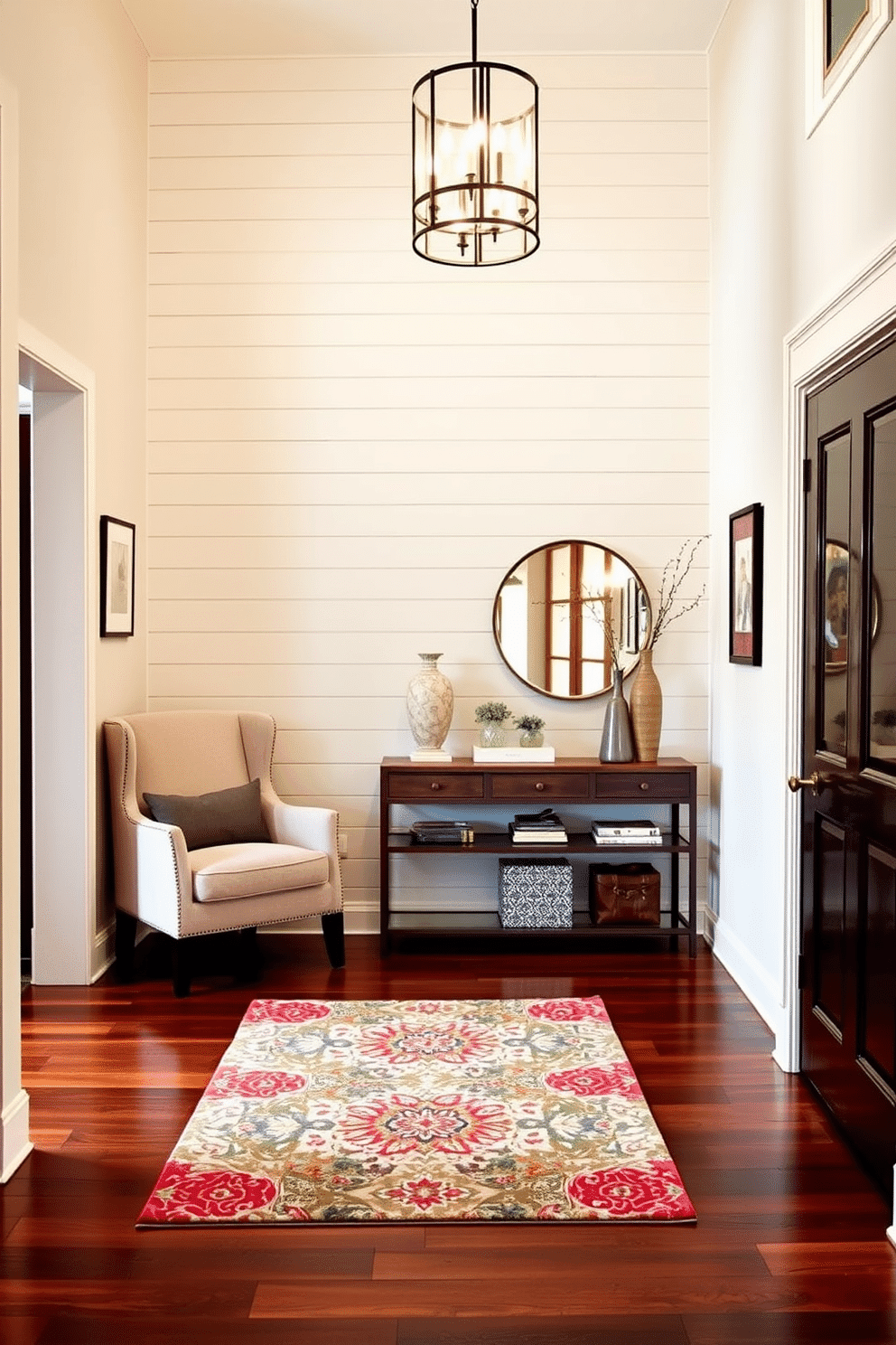 A stunning foyer entryway featuring an accent wall adorned with shiplap, painted in a soft, inviting hue. The space is illuminated by a modern chandelier, and a stylish console table is placed against the wall, topped with decorative accessories and a mirror. To the left, a cozy seating area includes a plush armchair and a small side table, creating a welcoming atmosphere. The flooring consists of rich hardwood, complemented by a vibrant area rug that adds warmth and texture to the entryway.