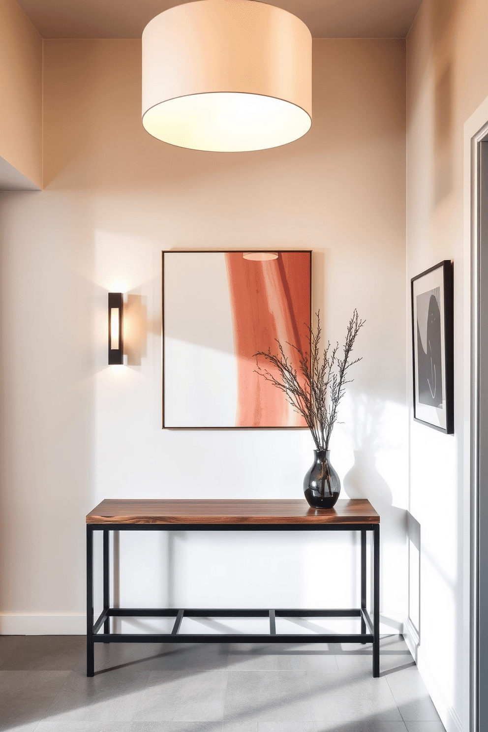 A sleek foyer entryway features modern lighting fixtures that create a warm and inviting atmosphere. The space showcases a minimalist console table in a rich wood finish, complemented by a striking pendant light hanging above, casting soft shadows on the walls.