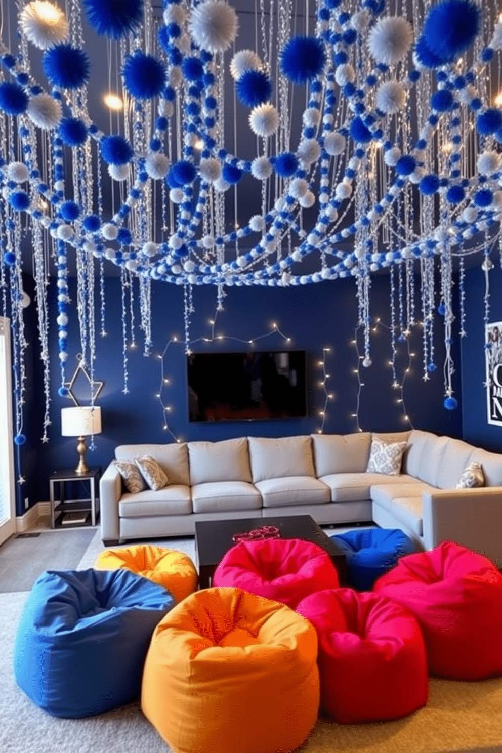 A vibrant game room adorned with a blue and silver pom-pom garland drapes elegantly across the ceiling, adding a festive touch. The walls are painted a deep navy, while a plush sectional sofa in light gray provides ample seating for friends and family. Twinkling fairy lights are interspersed among the pom-poms, creating a warm and inviting atmosphere. A large coffee table in the center is surrounded by colorful bean bags, perfect for casual gaming during Hanukkah celebrations.