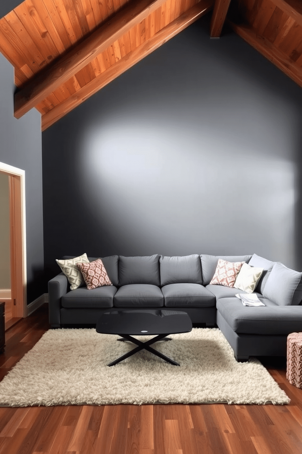 Accent wall with dark gray paint. The room features sloped ceilings with exposed wooden beams, creating a cozy and inviting atmosphere. A plush gray sectional sofa is positioned against the accent wall, complemented by colorful throw pillows. A modern coffee table with a glass top sits in the center, surrounded by a soft area rug that adds warmth to the space.