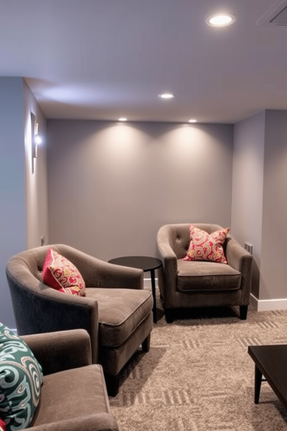 A stylish gray basement lounge features plush gray accent chairs adorned with vibrant, colorful cushions that add a pop of personality. The walls are painted a soft gray, while ambient lighting creates a warm and inviting atmosphere, perfect for relaxation or entertaining guests.