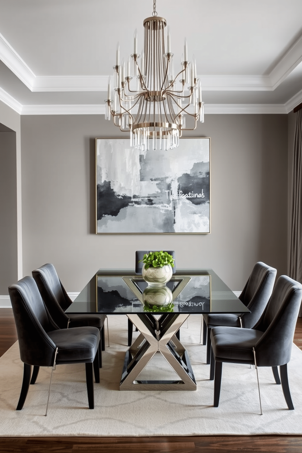 A sleek glass-top dining table serves as the centerpiece of this elegant gray dining room. Surrounding the table are plush, upholstered chairs in a soft charcoal fabric, creating a sophisticated and inviting atmosphere. The walls are painted in a warm gray tone, complemented by a statement chandelier that adds a touch of glamour. A large, abstract artwork in varying shades of gray and silver hangs prominently, enhancing the room's contemporary style.