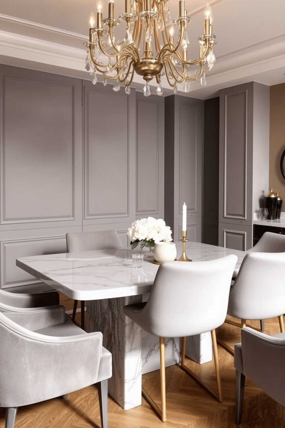 A contemporary dining room featuring a stunning gray dining table paired with elegant marble accents. The table is surrounded by plush upholstered chairs in a complementary shade, creating a harmonious and inviting atmosphere. The walls are adorned with soft gray tones, enhancing the room's sophistication. A statement chandelier hangs above the table, casting a warm glow over the space and highlighting the luxurious materials used throughout the design.