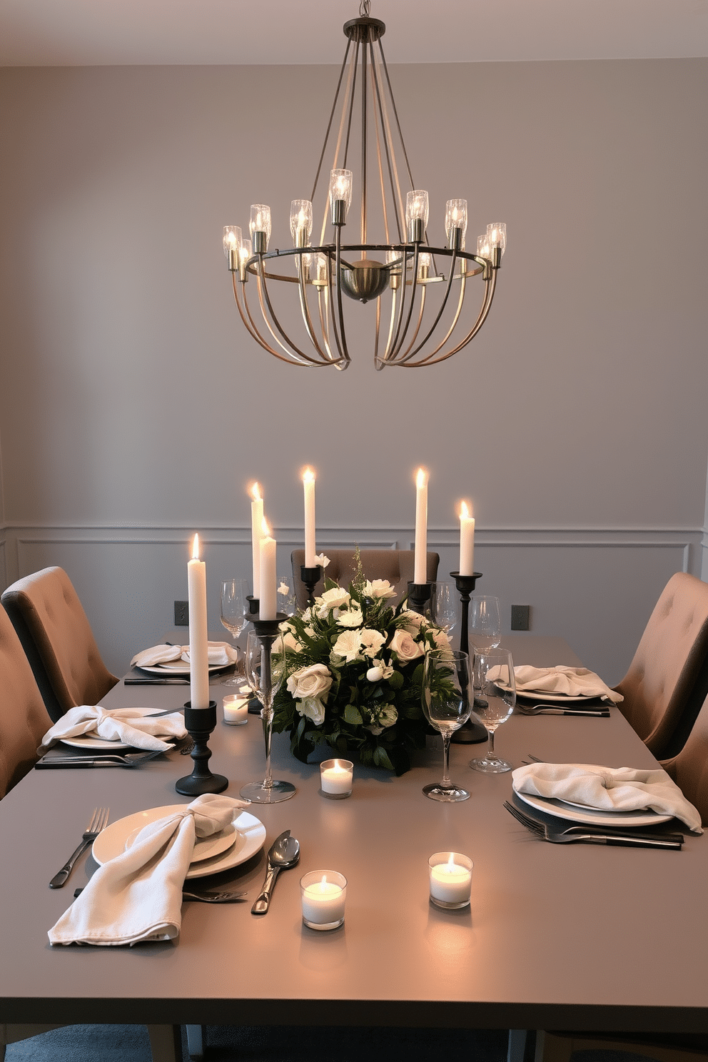 A candlelit tablescape is set on a sleek gray table, adorned with elegant dinnerware and soft linen napkins. Flickering candles in varied heights create a warm, inviting glow, while a lush floral centerpiece adds a touch of romance. The walls of the dining room are painted in a soft gray hue, complemented by plush gray upholstered chairs. A contemporary chandelier hangs above, casting a soft light that enhances the intimate atmosphere of the space.