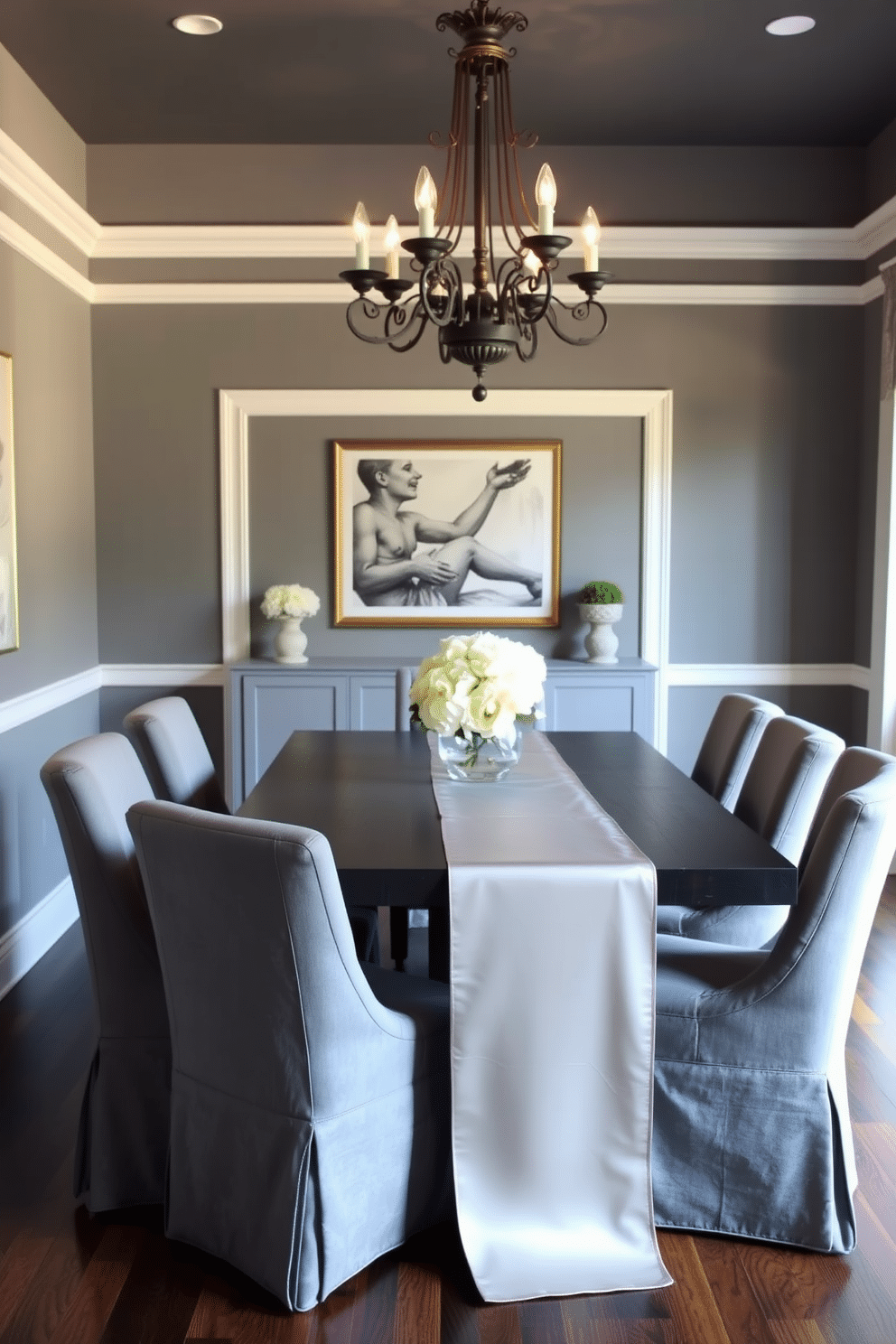 A sophisticated gray dining room featuring a sleek silver table runner that adds a touch of elegance. The dining table is surrounded by plush gray upholstered chairs, and an ornate chandelier hangs above, casting a warm glow over the space.