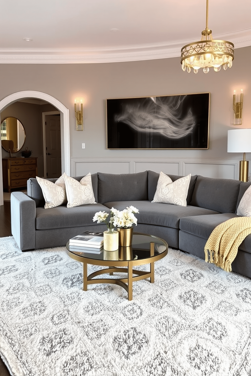 A stylish family room featuring an elegant gray and gold color palette. The walls are painted in a soft gray, complemented by gold accents in the decor and lighting fixtures. A plush gray sectional sofa is adorned with gold and white patterned throw pillows. A sleek coffee table with a gold base sits atop a soft, textured area rug that ties the room together.