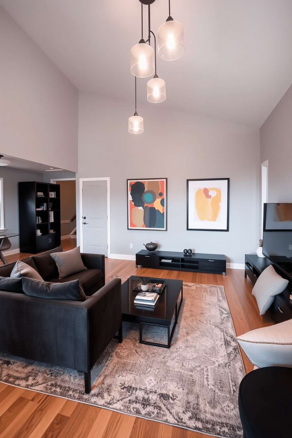 Light gray walls create a serene backdrop for a family room, complemented by dark accents in the furniture and decor. A plush charcoal sofa faces a sleek black coffee table, while a dark wood entertainment unit adds depth to the space. Soft lighting fixtures hang from the ceiling, casting a warm glow over the room. A large area rug in a muted pattern anchors the seating area, while framed artwork with bold colors adorns the walls, adding visual interest.