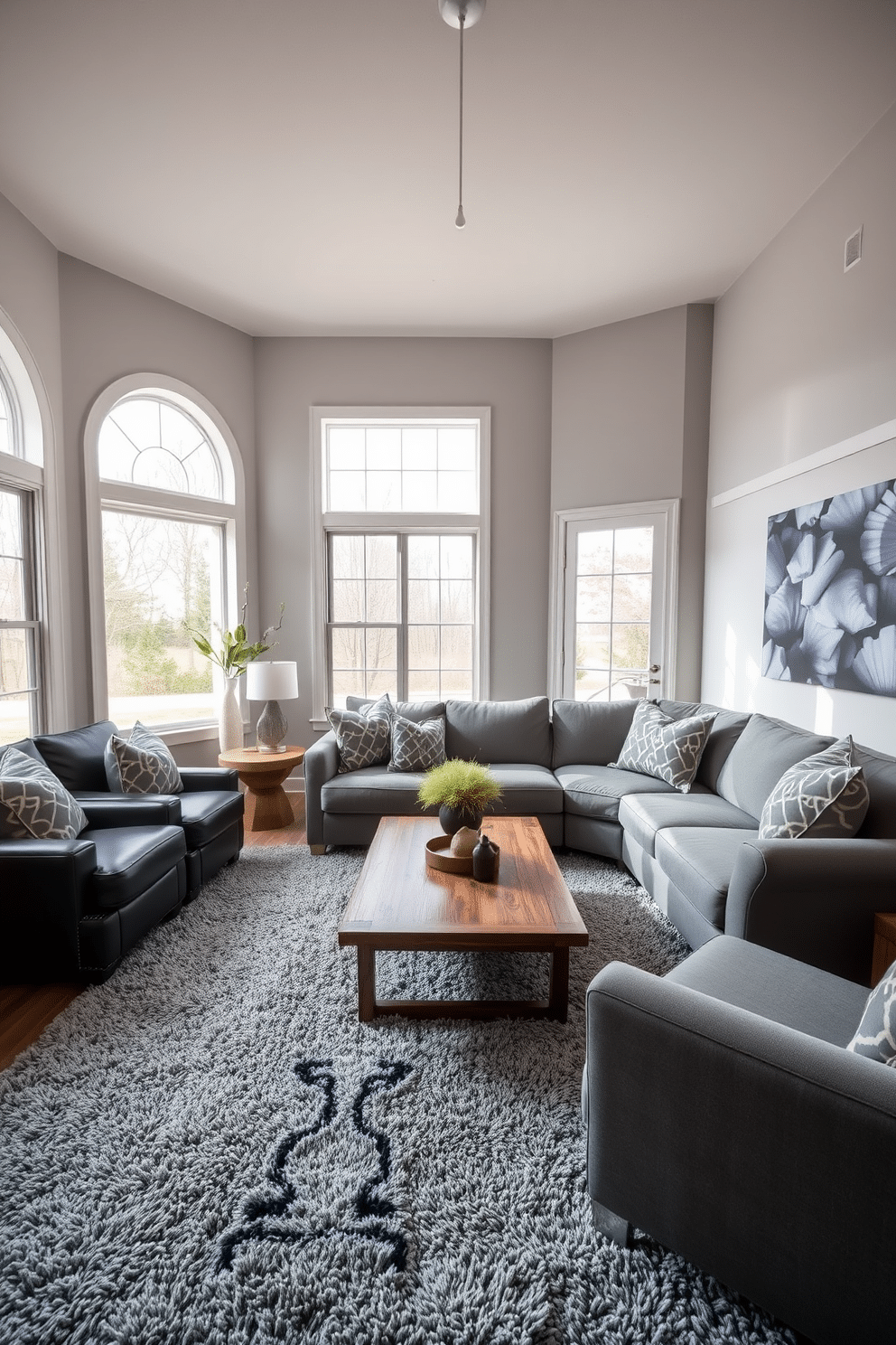 A cozy family room featuring layered textures, highlighted by a plush gray rug that anchors the space. The walls are adorned with soft, neutral tones, complemented by a mix of fabric and leather furniture in varying shades of gray. A large sectional sofa invites relaxation, accented with patterned throw pillows for added depth. Natural light floods the room through oversized windows, enhancing the warmth of the wooden coffee table at the center.