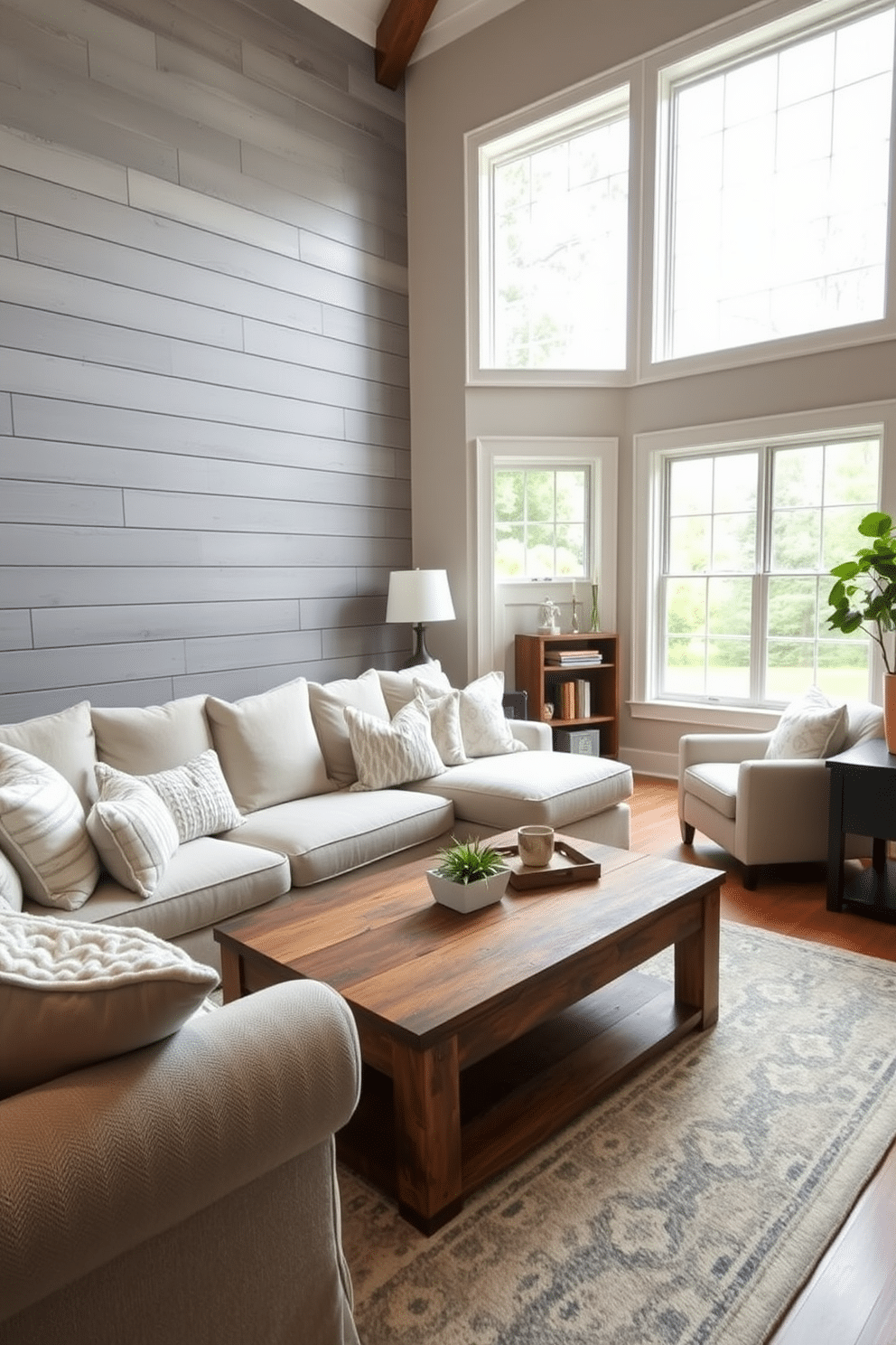 A stylish family room featuring an accent wall adorned with gray shiplap panels, creating a warm and inviting atmosphere. The room is furnished with a plush sectional sofa in a light fabric, complemented by a rustic coffee table made from reclaimed wood. Natural light floods the space through large windows, showcasing a cozy reading nook with a comfortable armchair and a small bookshelf. Soft, textured throw pillows in varying shades of gray and white add depth and comfort to the seating area.