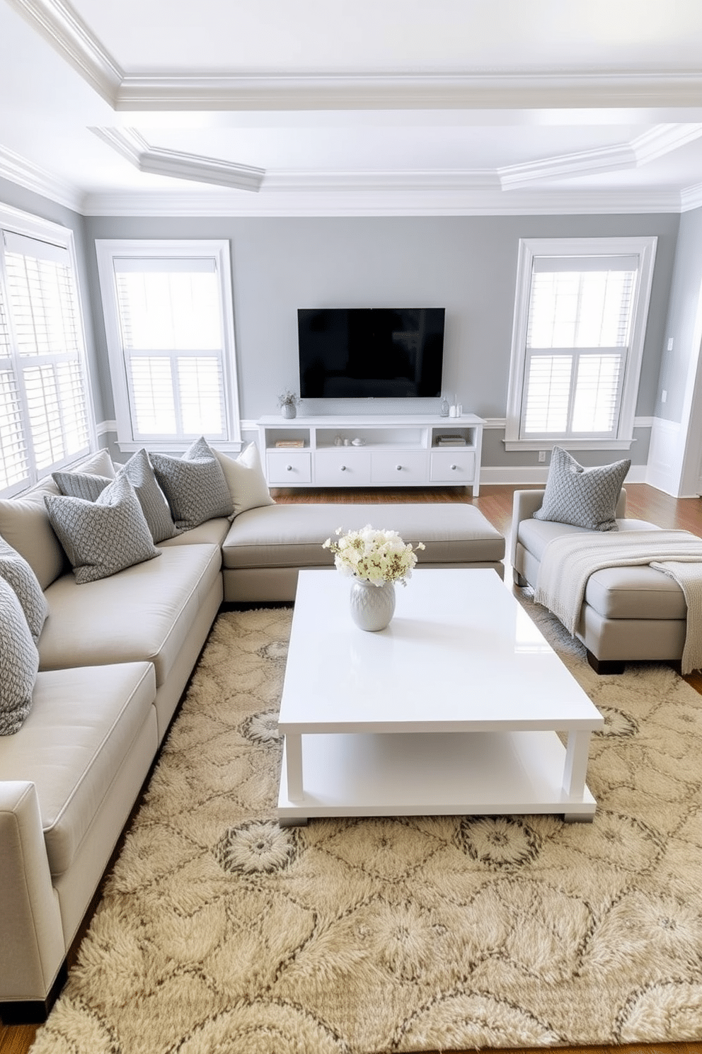 A harmonious gray and white family room features a plush sectional sofa adorned with textured pillows in varying shades of gray. A sleek white coffee table sits atop a soft area rug, creating a cozy focal point in the space. The walls are painted in a soft gray, complemented by white crown molding that adds an elegant touch. Large windows allow natural light to flood the room, highlighting a minimalist entertainment unit against one wall.