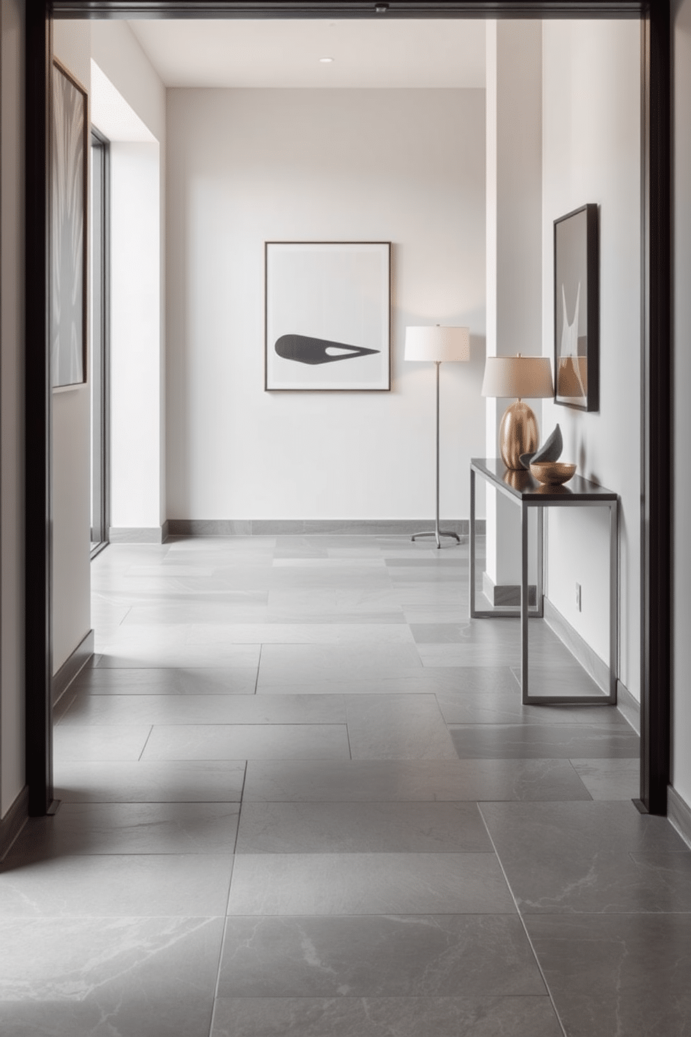 A modern foyer featuring gray stone tiles that create a sleek and sophisticated floor. The walls are adorned with minimalist artwork, and a stylish console table sits against one side, complemented by a contemporary lamp.