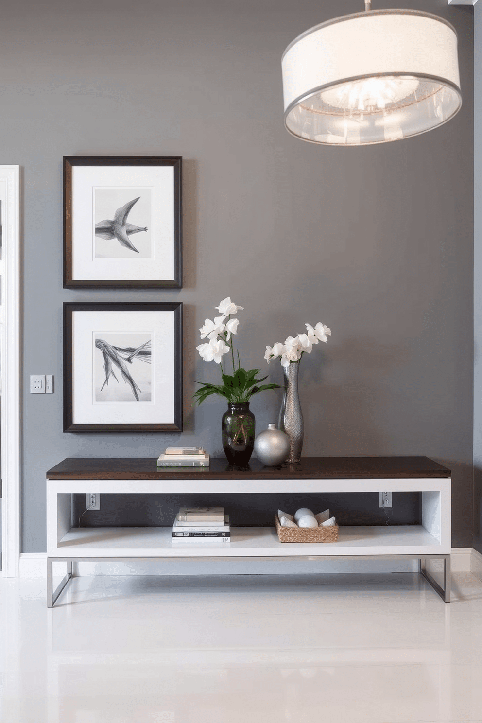 A stylish foyer featuring a gray accent wall adorned with framed artwork that adds a touch of sophistication. The space includes a sleek console table topped with decorative items, and a modern light fixture hangs above, illuminating the area beautifully.