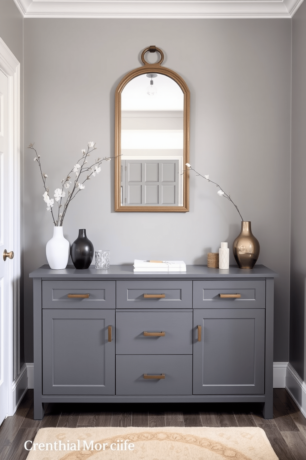 A sleek gray sideboard serves as a stylish organizational piece in the entryway, featuring clean lines and a minimalist design. The foyer is adorned with subtle gray tones, complemented by a statement mirror above the sideboard and a few decorative items that add a personal touch.