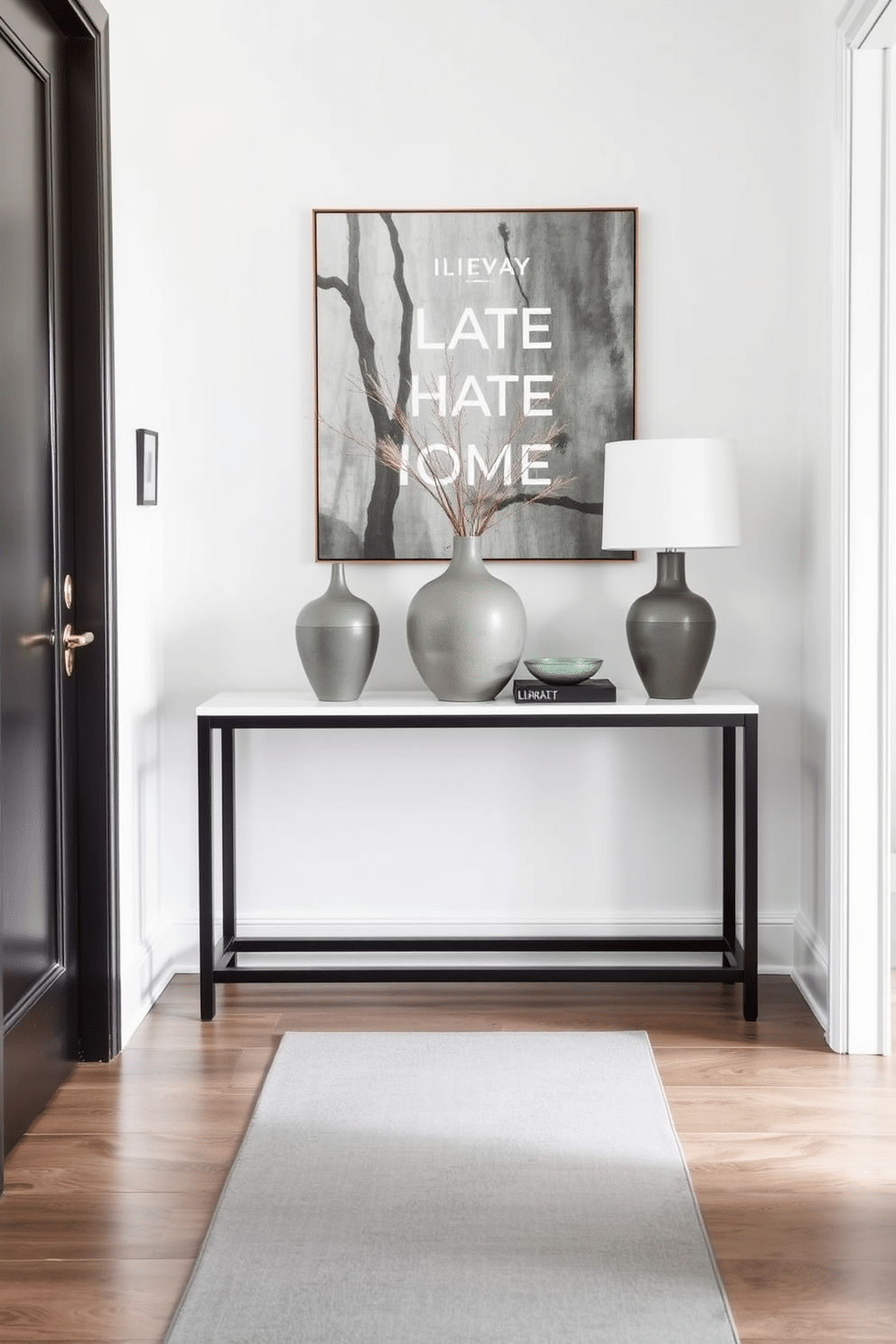 A stylish foyer featuring a sleek console table adorned with elegant gray decorative vases. The walls are painted in a soft white, complemented by a chic gray runner that leads to the entrance, creating a welcoming atmosphere.