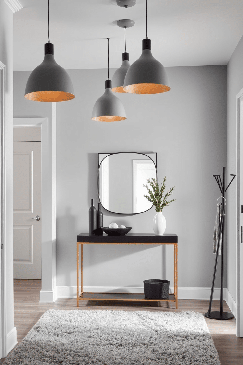 A contemporary entryway features sleek gray pendant lights suspended from the ceiling, casting a warm glow over the space. The foyer is adorned with a stylish console table against the wall, topped with decorative items and a large mirror that enhances the room's brightness. The walls are painted in a soft gray hue, complementing the modern aesthetic, while a plush area rug adds texture underfoot. A minimalist coat rack stands to one side, providing functionality without compromising the design elegance.