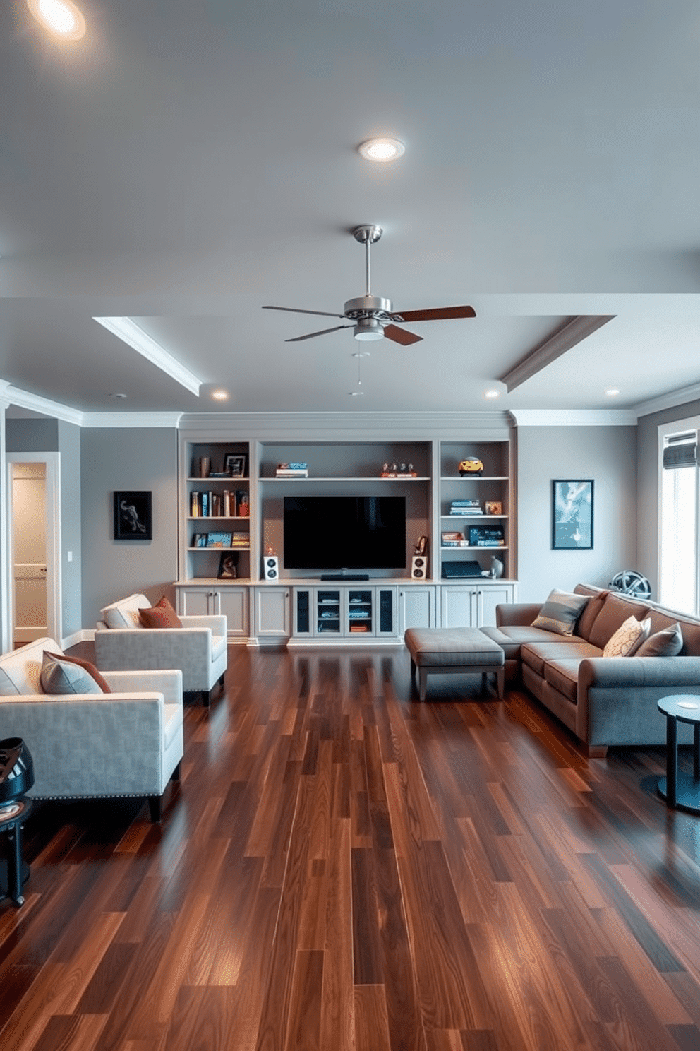 A spacious game room with an open layout that encourages social interaction and relaxation. The walls are painted in a soft gray hue, complemented by plush seating arrangements and a large sectional sofa. The flooring features a sleek dark wood finish, providing warmth and contrast to the light-colored walls. A custom-built entertainment center houses a large flat-screen TV, surrounded by shelves filled with games and collectibles.