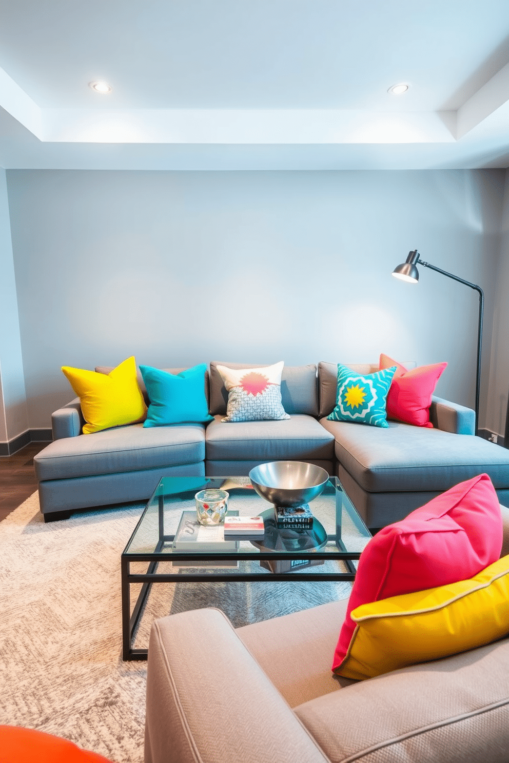 Bright throw pillows in vibrant hues of yellow, teal, and coral are strategically placed on a sleek gray sectional sofa, creating an inviting focal point in the room. The walls are painted a soft gray, complementing the colorful accents while maintaining a modern aesthetic. A contemporary coffee table with a glass top sits in the center, adorned with a few stylish coasters and a decorative bowl. The lighting is soft yet ample, with recessed lights illuminating the space and a statement floor lamp adding a touch of elegance.