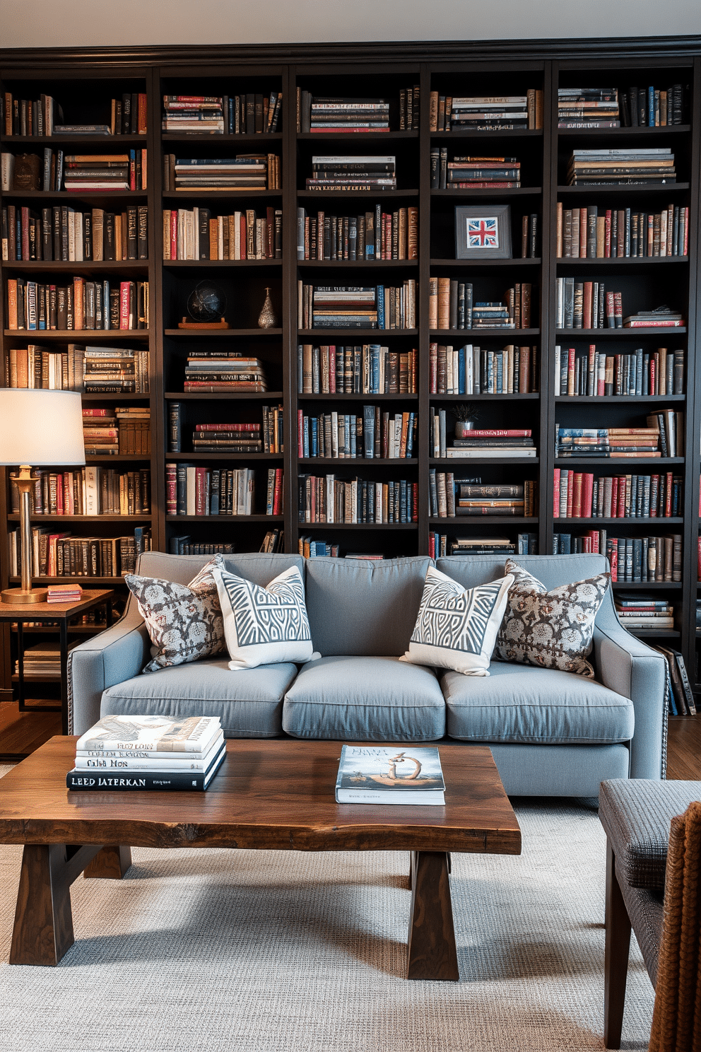 A cozy home library featuring a mix of gray and wood elements. The walls are painted a soft gray, complemented by dark wooden bookshelves filled with an array of books and decorative items. In the center, a plush gray sofa invites relaxation, adorned with patterned throw pillows. A rustic wooden coffee table sits in front, topped with a stylish lamp and a few art books for inspiration.