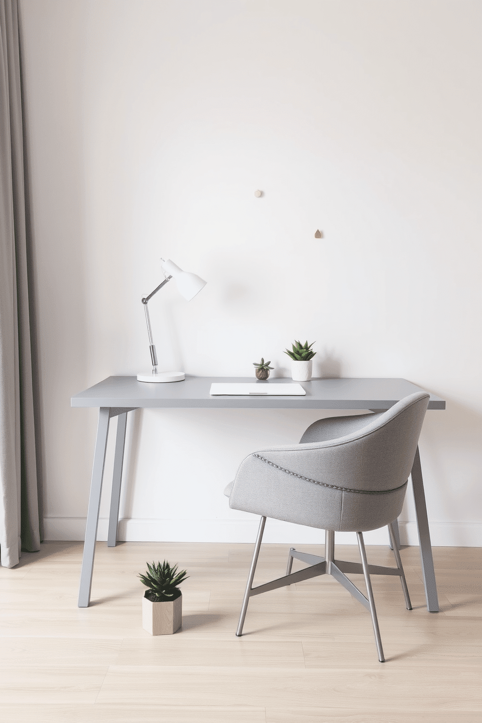 A minimalist gray desk is positioned against a soft white wall, complemented by geometric decor pieces scattered throughout the space. A sleek desk lamp with clean lines illuminates the workspace, while a plush gray chair invites comfort and style. The floor is adorned with a light wood finish, enhancing the airy feel of the home office. A small potted succulent sits beside the desk, adding a touch of greenery to the refined atmosphere.