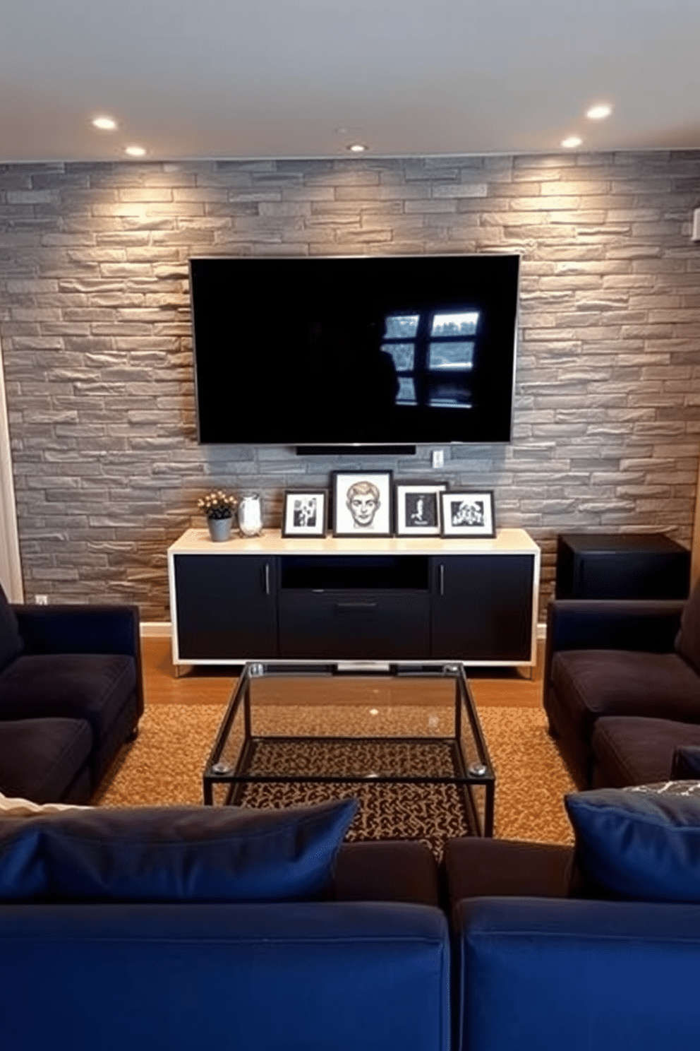 Accent wall with gray brick or stone. The space features a plush sectional sofa in a deep navy hue, complemented by a sleek glass coffee table at the center. Soft ambient lighting illuminates the room, highlighting the texture of the gray brick wall. A large flat-screen TV is mounted above a modern console, surrounded by framed artwork that adds personality to the man cave.