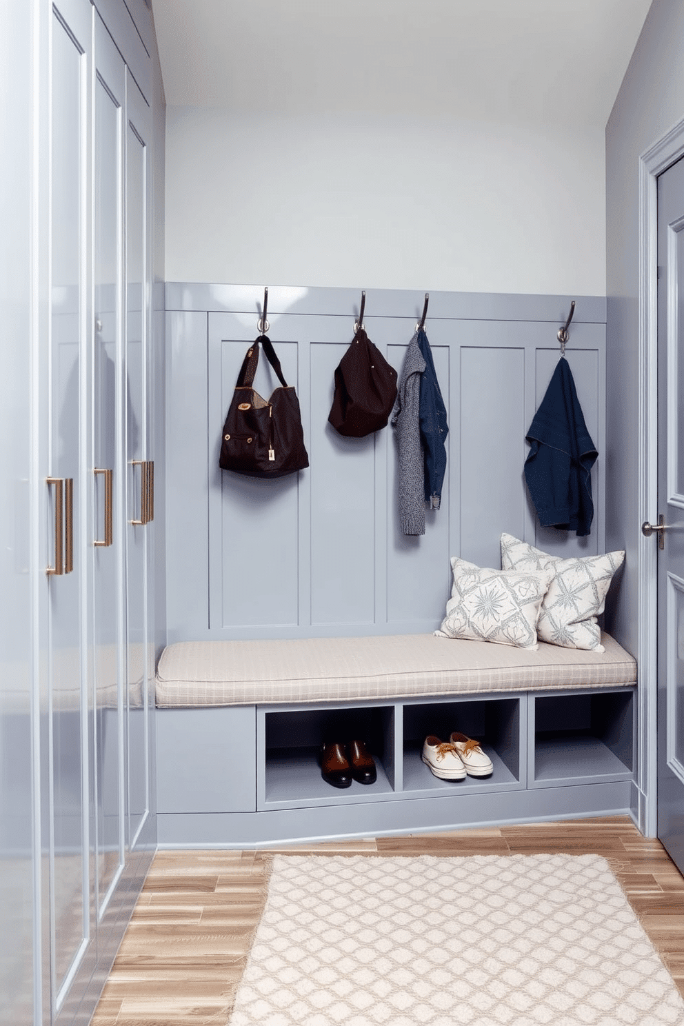 A stylish gray mudroom features sleek lockers designed for family storage, each with a polished finish and subtle hardware. The space is accented with a cozy bench upholstered in a soft fabric, providing a comfortable spot to sit while removing shoes. The walls are painted in a light gray hue, creating a serene backdrop for the lockers, which are arranged neatly along one side. A patterned rug adds warmth to the floor, while hooks above the bench hold jackets and bags, keeping the area organized and inviting.