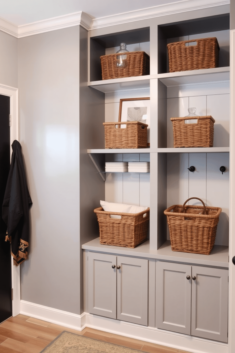 A stylish gray mudroom features wall-mounted shelves that provide both function and aesthetic appeal. The shelves are adorned with neatly arranged baskets and decorative items, creating an organized yet inviting space.