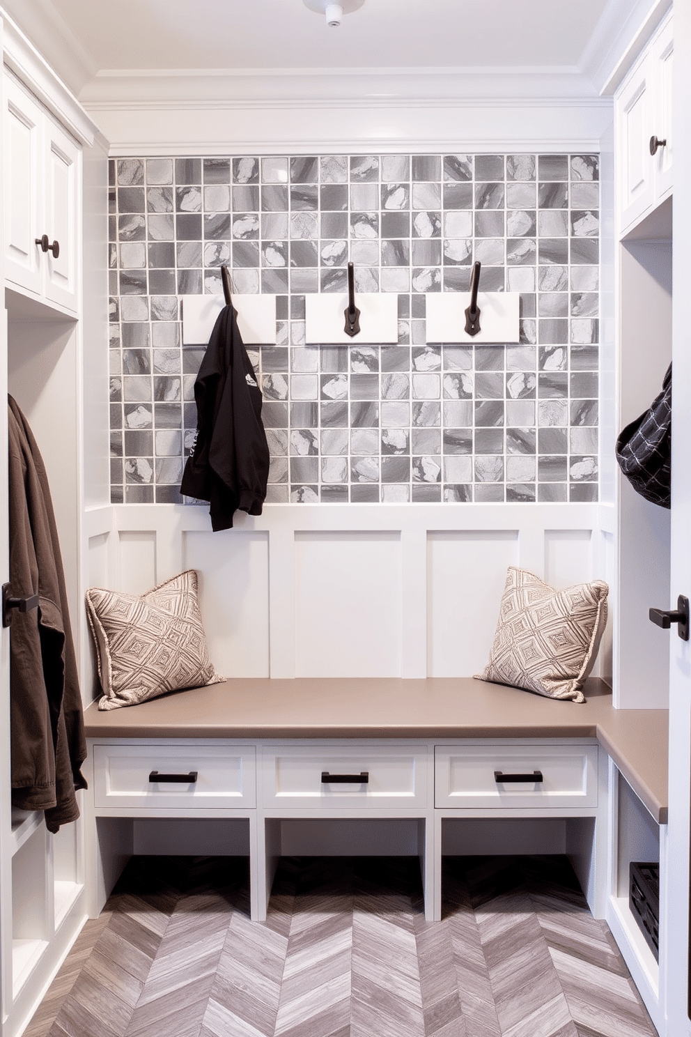 A stylish mudroom featuring gray accent tiles arranged in a herringbone pattern, creating a modern and inviting atmosphere. The space includes built-in benches with plush cushions, ample storage cubbies, and hooks for coats, all designed to enhance functionality and aesthetic appeal.