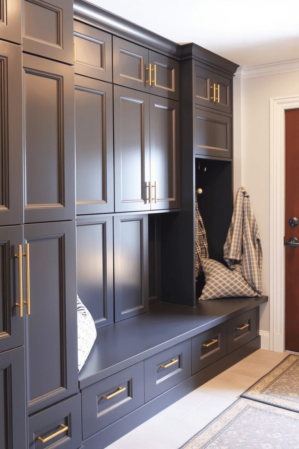 A stylish mudroom featuring dark gray cabinetry accented with elegant gold hardware. The space is designed for functionality, with built-in benches and hooks for coats, creating an inviting and organized entryway.