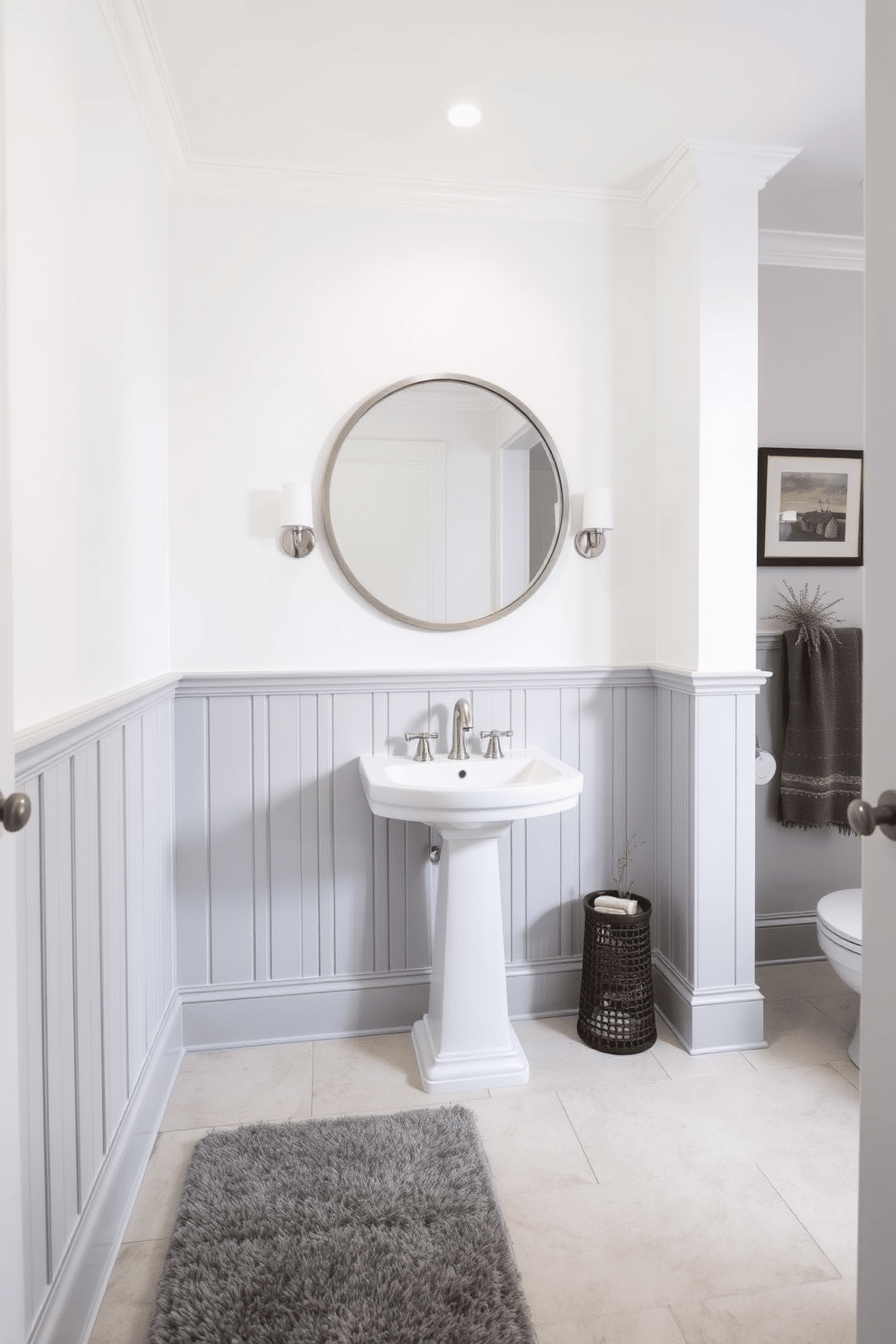 Light gray wainscoting lines the lower half of the walls, creating a refined backdrop for the contrasting colors above. The ceiling is painted in a soft white, enhancing the room's brightness and making the space feel larger. A sleek pedestal sink sits against the wainscoting, paired with a stylish wall-mounted faucet. Above the sink, a large round mirror framed in brushed nickel reflects the elegant design of the room. The floor is adorned with large, light-colored tiles that complement the gray tones, while a plush rug adds warmth underfoot. Thoughtful decor elements, such as a small potted plant and tasteful wall art, bring personality to the space.