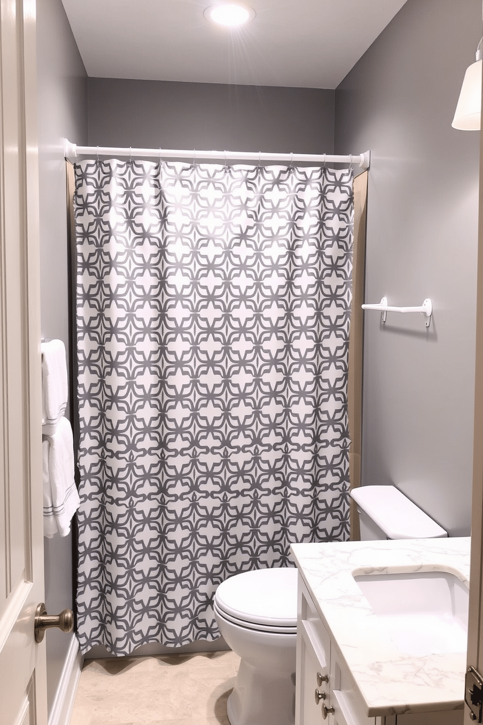 A chic powder room featuring a gray and white patterned shower curtain that adds a touch of elegance. The walls are painted in a soft gray, complemented by sleek white fixtures and a minimalist vanity with a polished marble top.