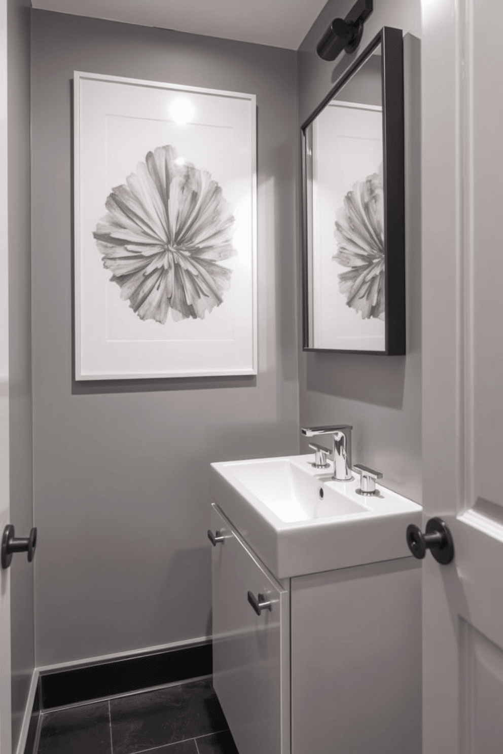 A chic gray powder room featuring bold gray artwork that adds a striking focal point to the space. The walls are painted in a soft gray tone, complemented by a sleek, modern sink and minimalist fixtures. The floor is adorned with dark tiles that contrast beautifully with the lighter walls. A stylish mirror with a thin black frame hangs above the sink, reflecting the artwork and enhancing the room's overall elegance.