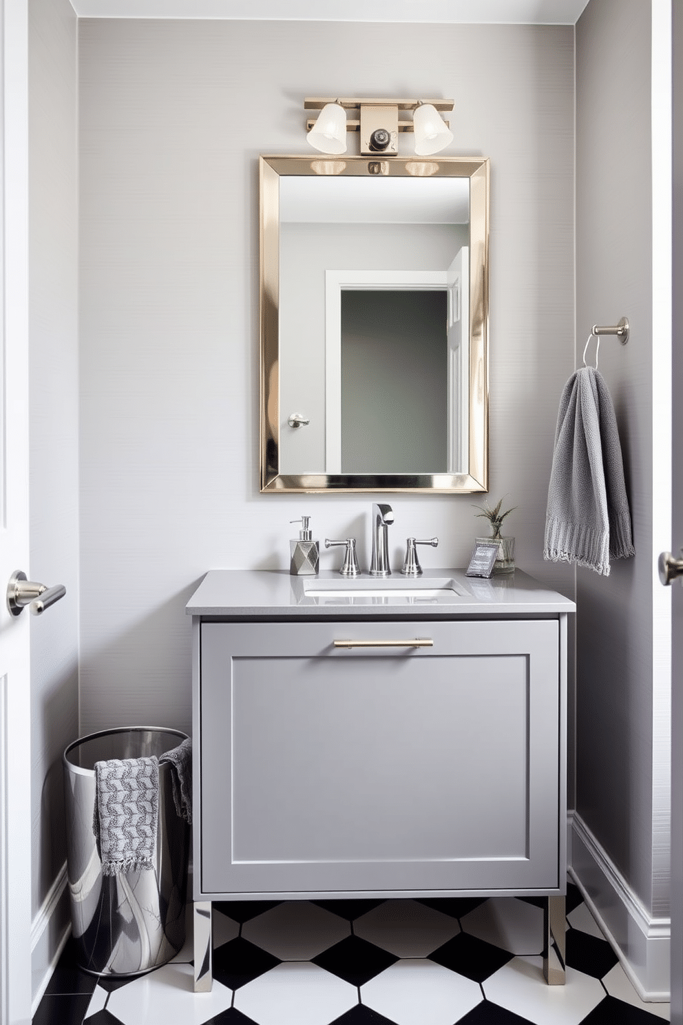 A chic powder room features a sleek gray vanity with metallic accents, complemented by a stylish mirror with a brushed nickel frame. The walls are adorned with a soft gray wallpaper that has a subtle sheen, while the floor is covered in elegant black and white tiles. Incorporated into the design are gray accessories, including a geometric soap dispenser and a metallic wastebasket that adds a touch of sophistication. A luxurious hand towel in a deeper gray hue hangs neatly on a polished chrome towel bar, enhancing the overall modern aesthetic.