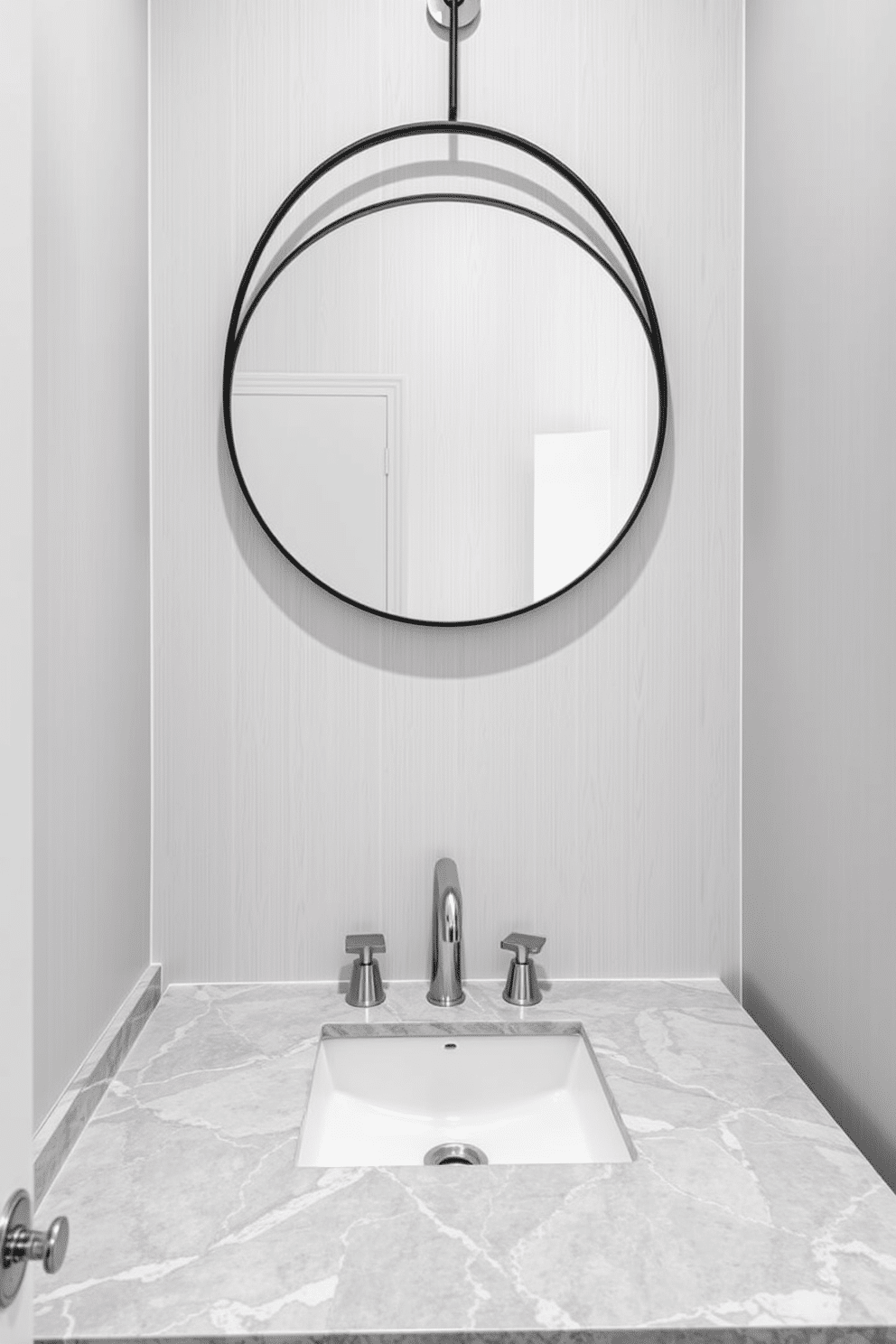 A chic powder room featuring a stunning gray marble countertop that adds a touch of luxury. The walls are adorned with soft gray wallpaper, creating a serene backdrop for the elegant design. A sleek, modern sink is integrated into the marble countertop, complemented by polished chrome fixtures. A stylish round mirror with a thin black frame hangs above, reflecting the room's sophisticated ambiance.