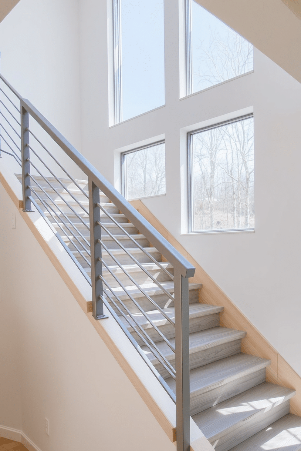 A sleek and modern gray metal stair railing elegantly contrasts with the light wooden staircase it adorns. The railing features clean lines and geometric shapes, providing a minimalist aesthetic that enhances the contemporary feel of the space. The staircase itself showcases a combination of gray treads and risers, creating a harmonious flow with the railing design. Large windows nearby allow natural light to illuminate the staircase, highlighting the textures and colors of the materials used.